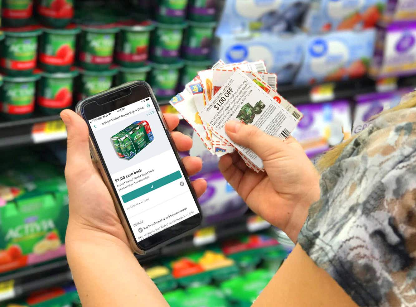 person holding coupons and showing ibotta app with activia product