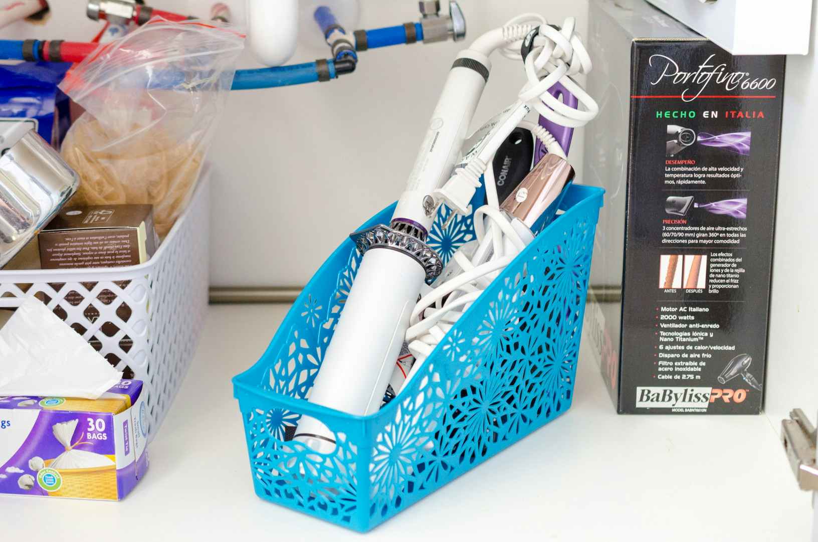 a magazine organizer under a bathroom sink with curling irons inside 