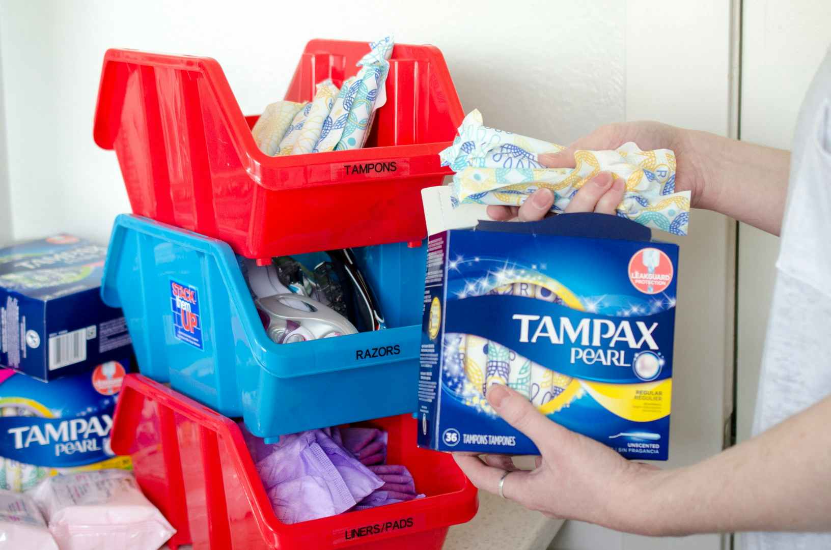 a person adding tampons to a three tired stacked organizer 