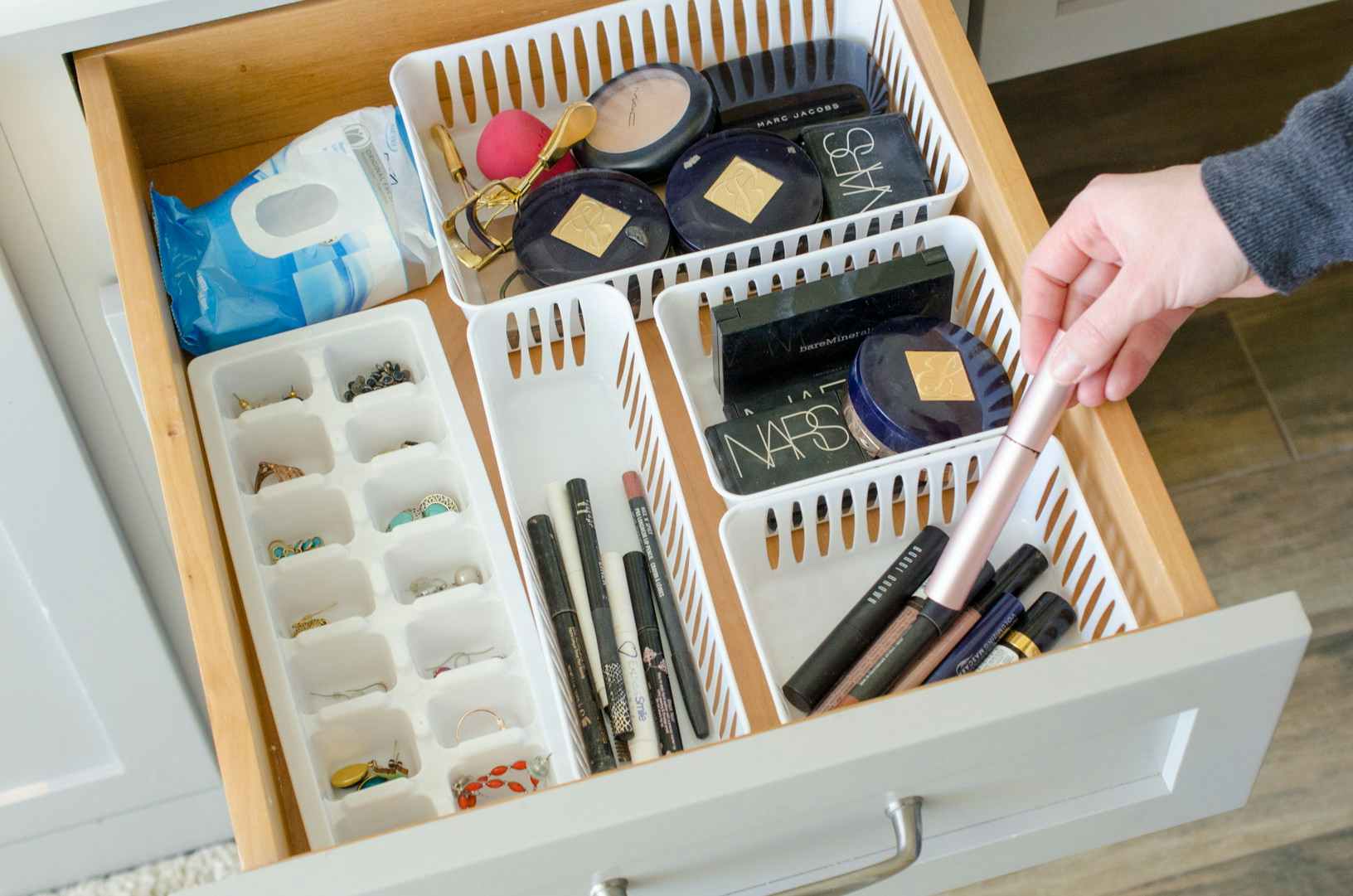 a bathroom drawer filled with plastic organizers filled with makeup and jewlery 