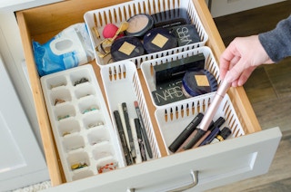 a bathroom drawer filled with plastic organizers filled with makeup and jewlery