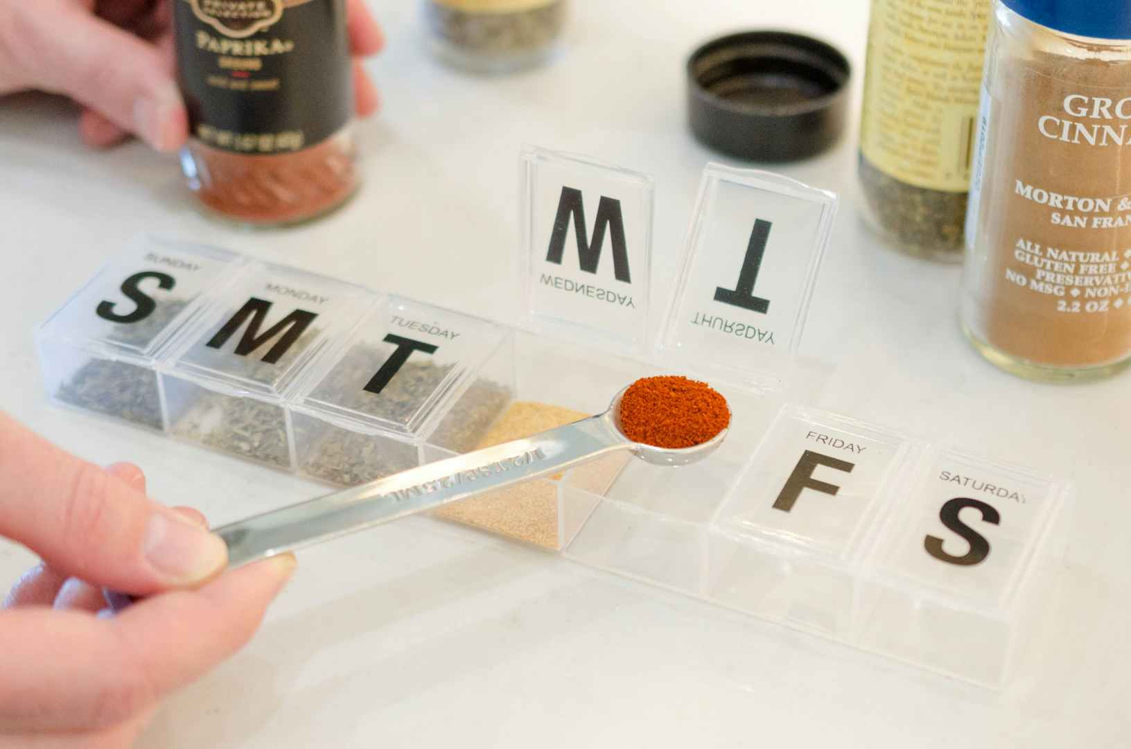 and person adding spices into a pill holder 