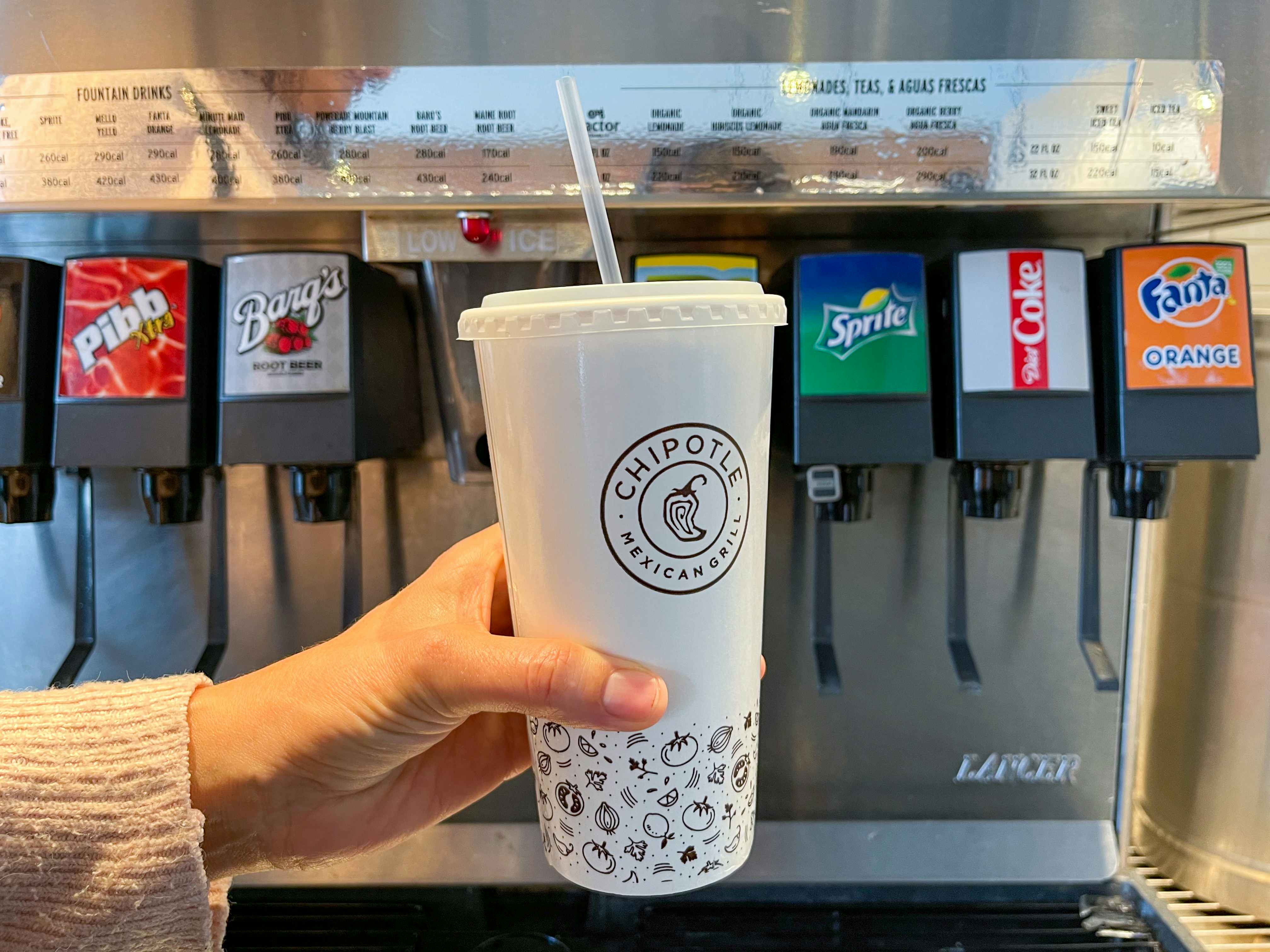 someone holding cup in front of fountain soda