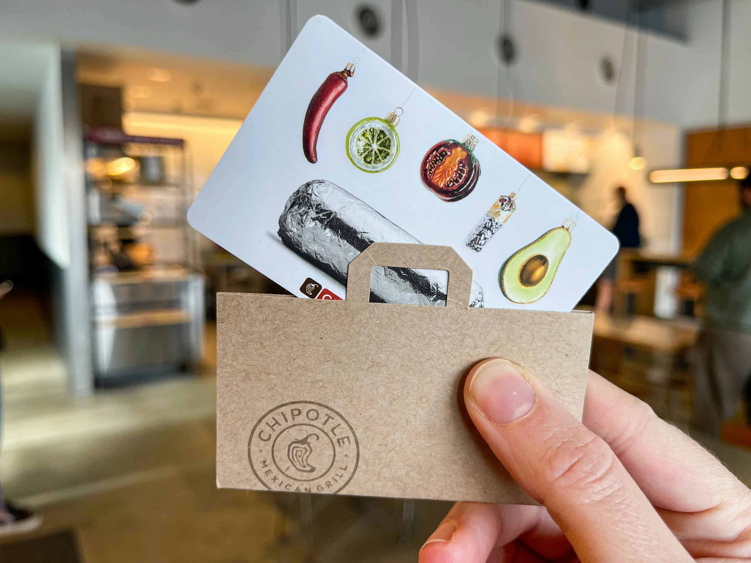 someone holding chipotle gift card inside a Chipotle.