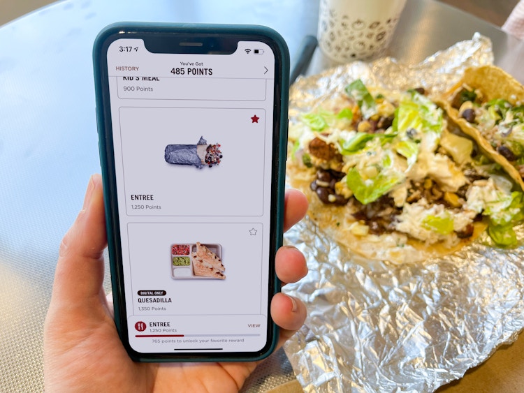 someone holding phone with chipotle app next to burrito bowl