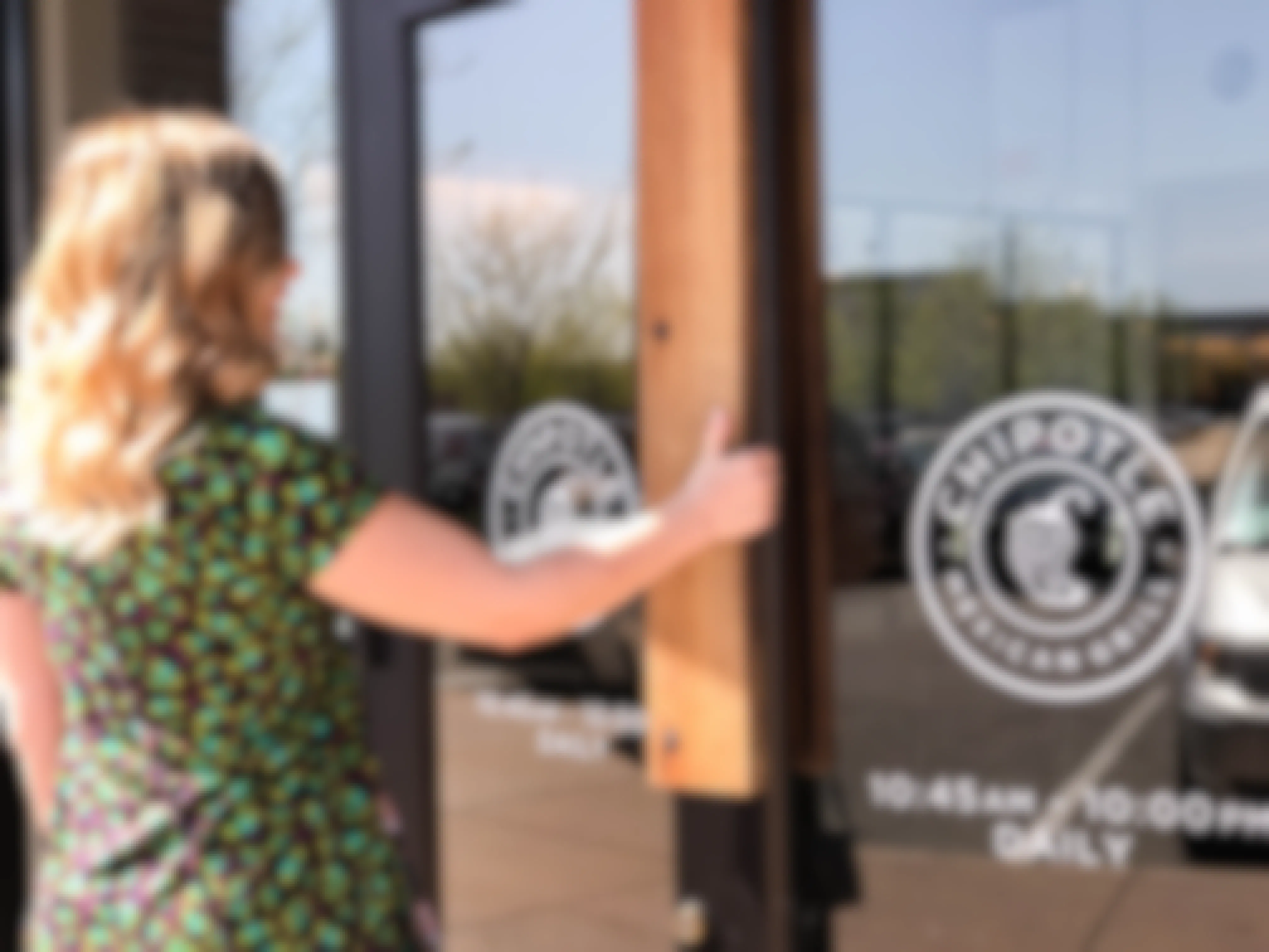 Woman opening the door to Chipotle, which she'll be able to do because it's one of the restaurants open on 4th of July
