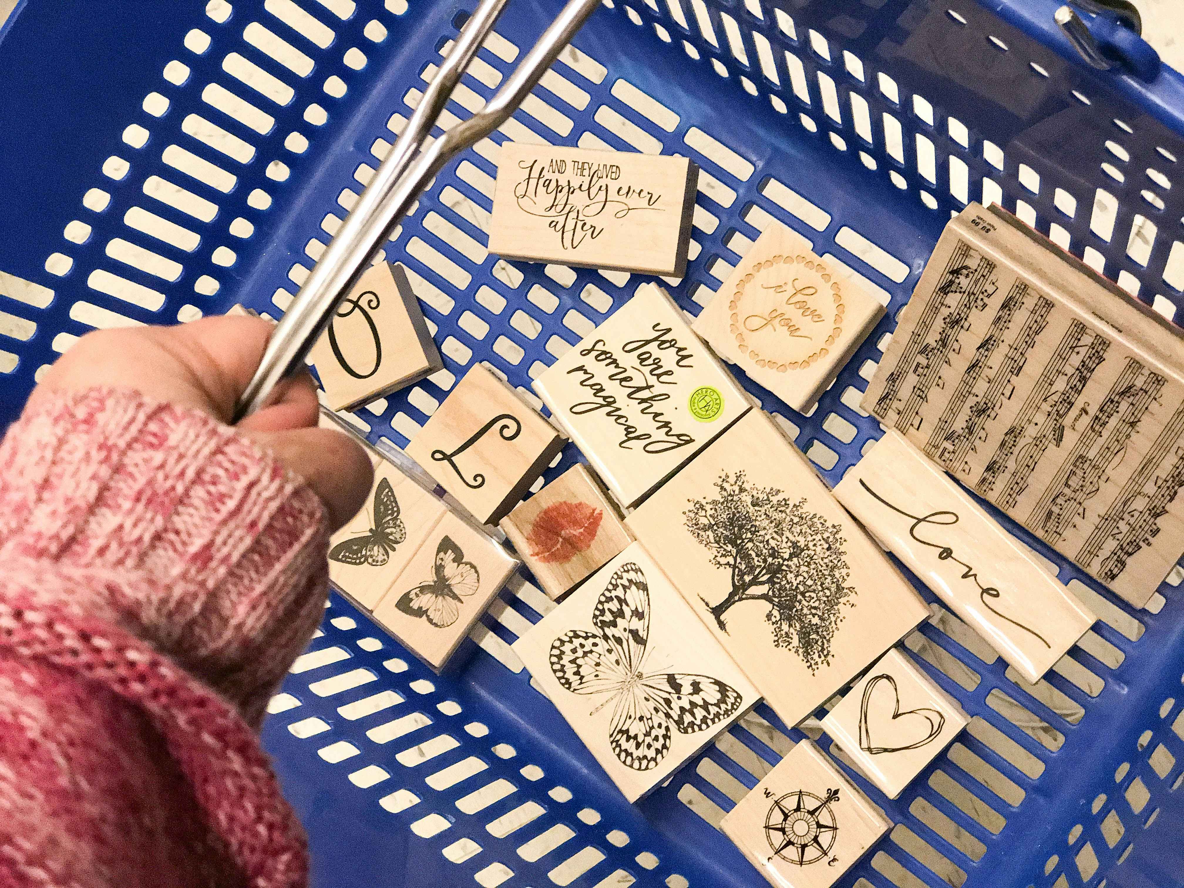 a person carrying a basket full of stamps from hobby lobby