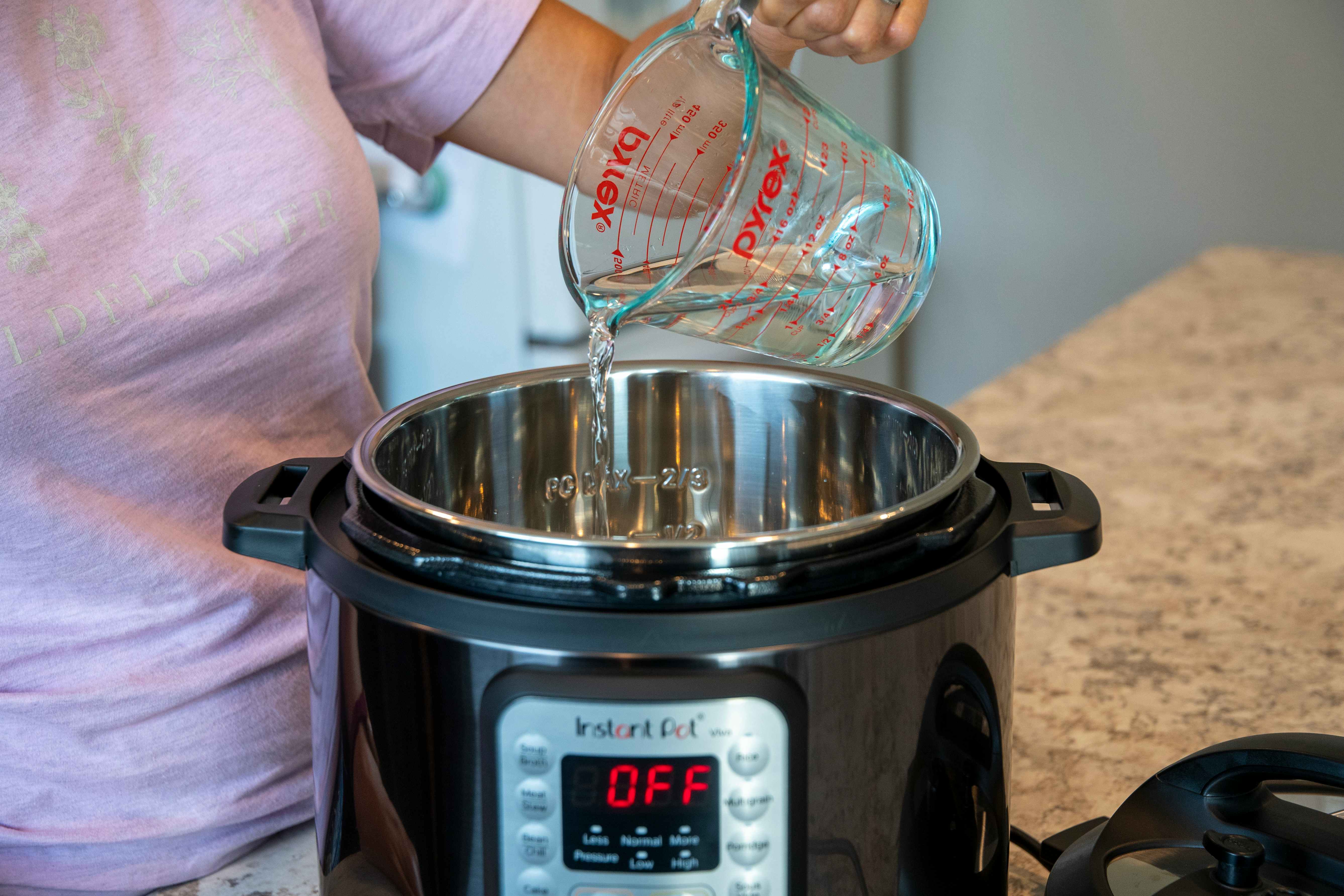 person adding water to instant pot to meet max fill line