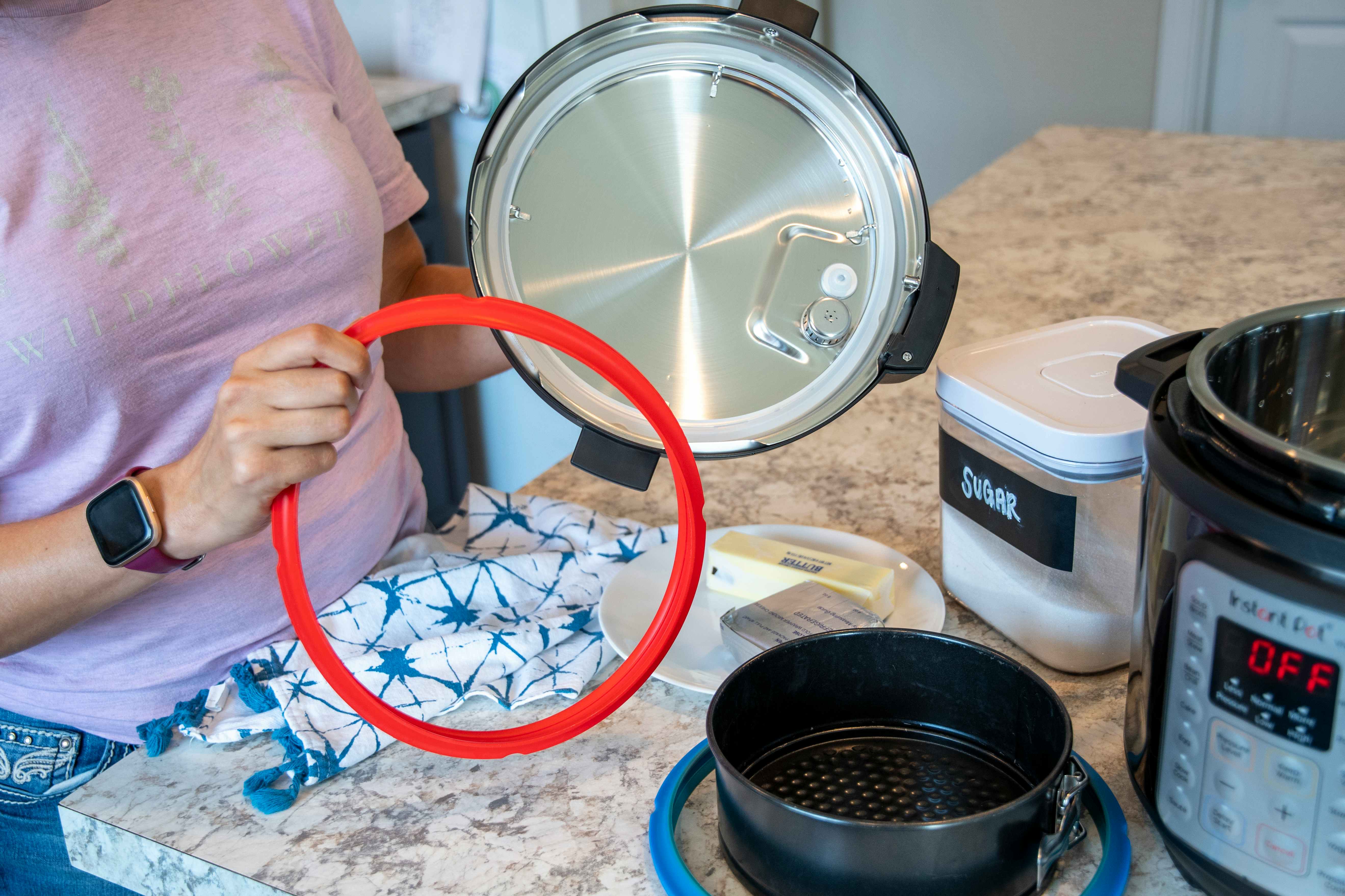 person holding red instant pot seal ring next to appliance