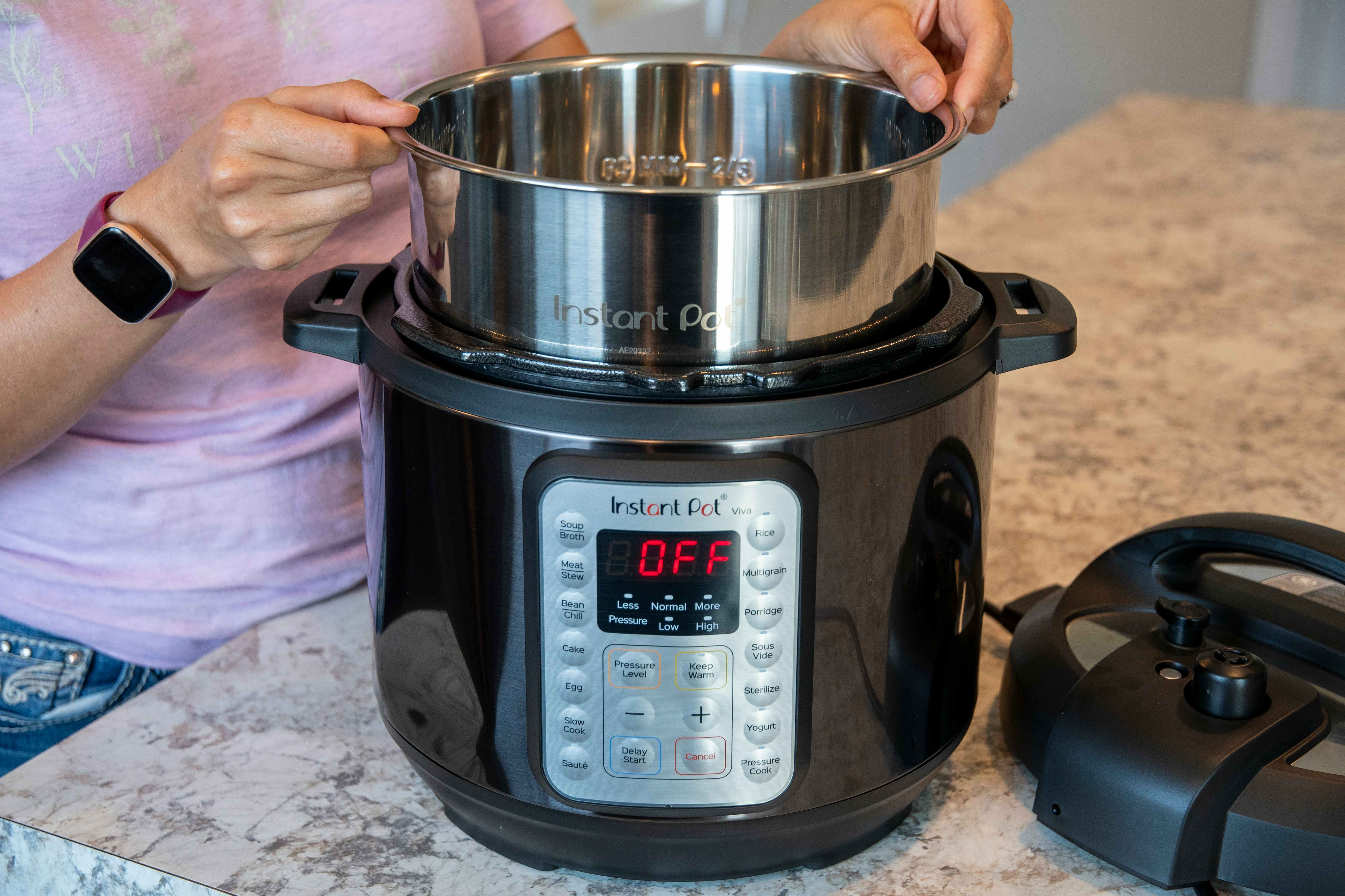 A person adding the inner pot back into an instant pot pressure cooker