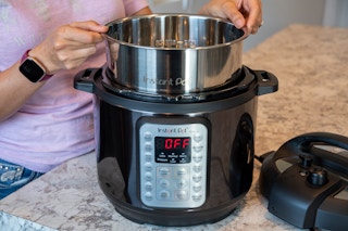 A person adding the inner pot back into an instant pot pressure cooker