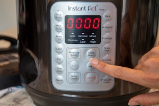 person pressing keep warm setting on control panel of instant pot