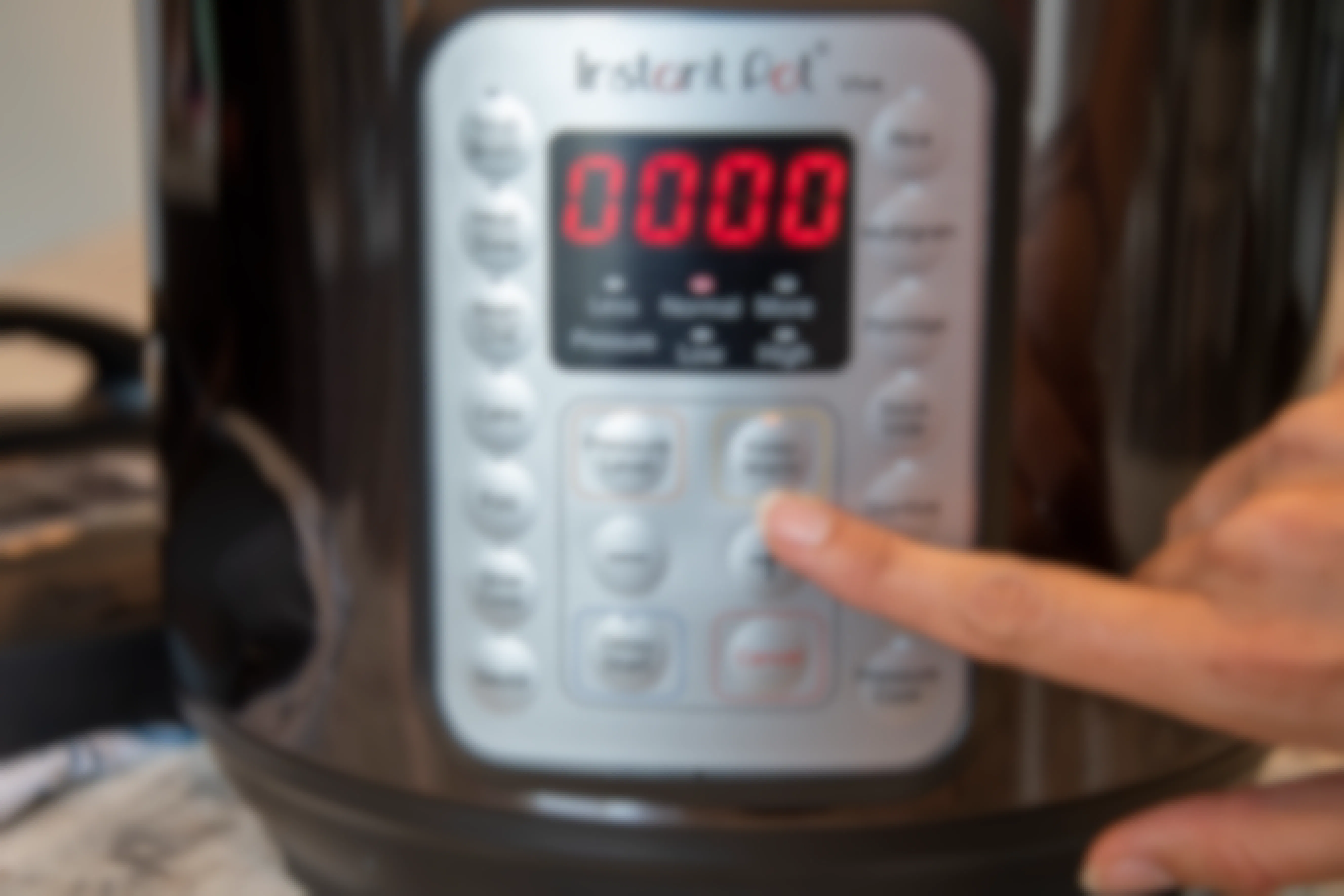 person pressing keep warm setting on control panel of instant pot