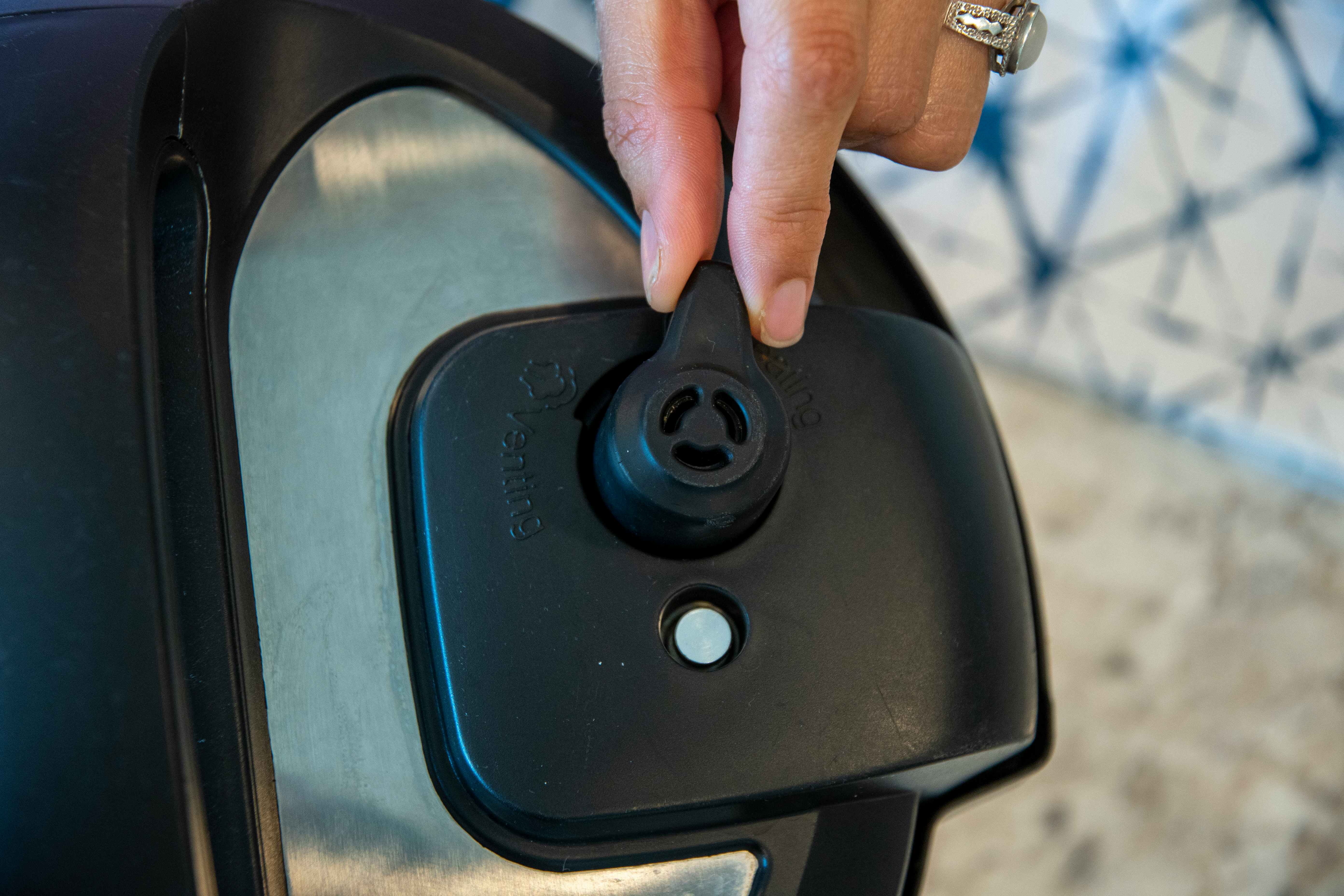 persons hand sealing steam valve on instant pot