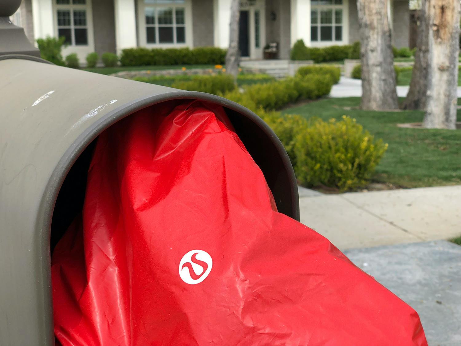 a red lululemon shipping bag shoved into a residential mailbox