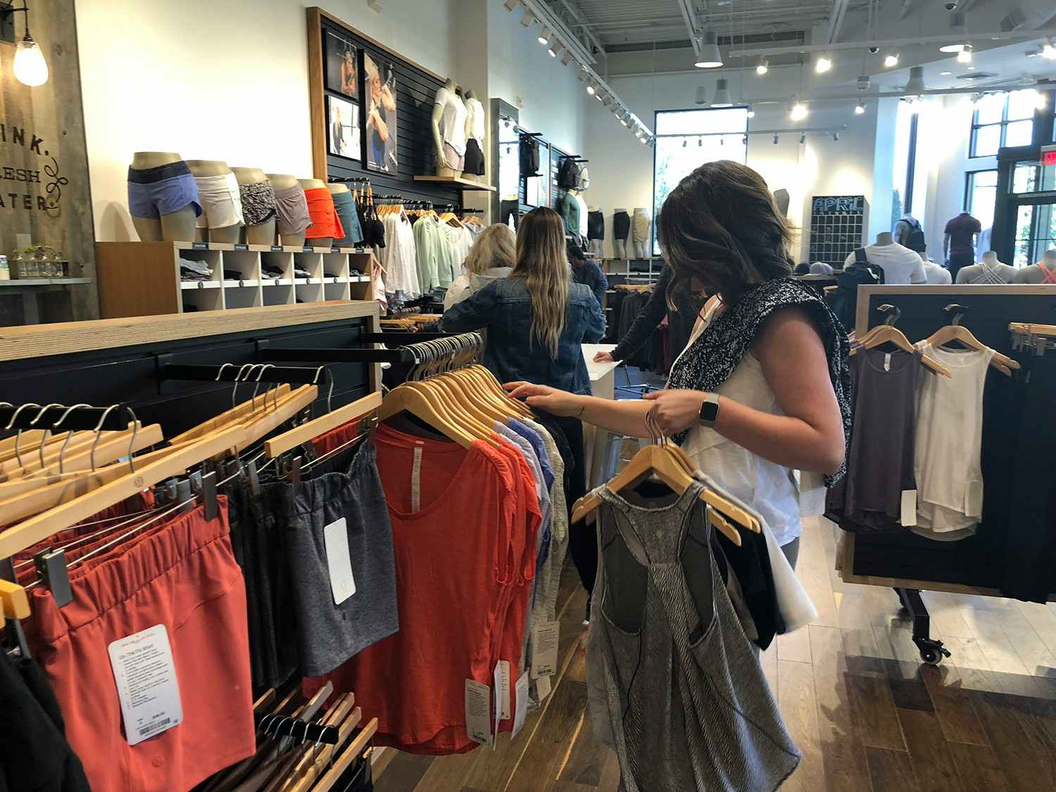 A woman looking through a rack of clothes at lululemon