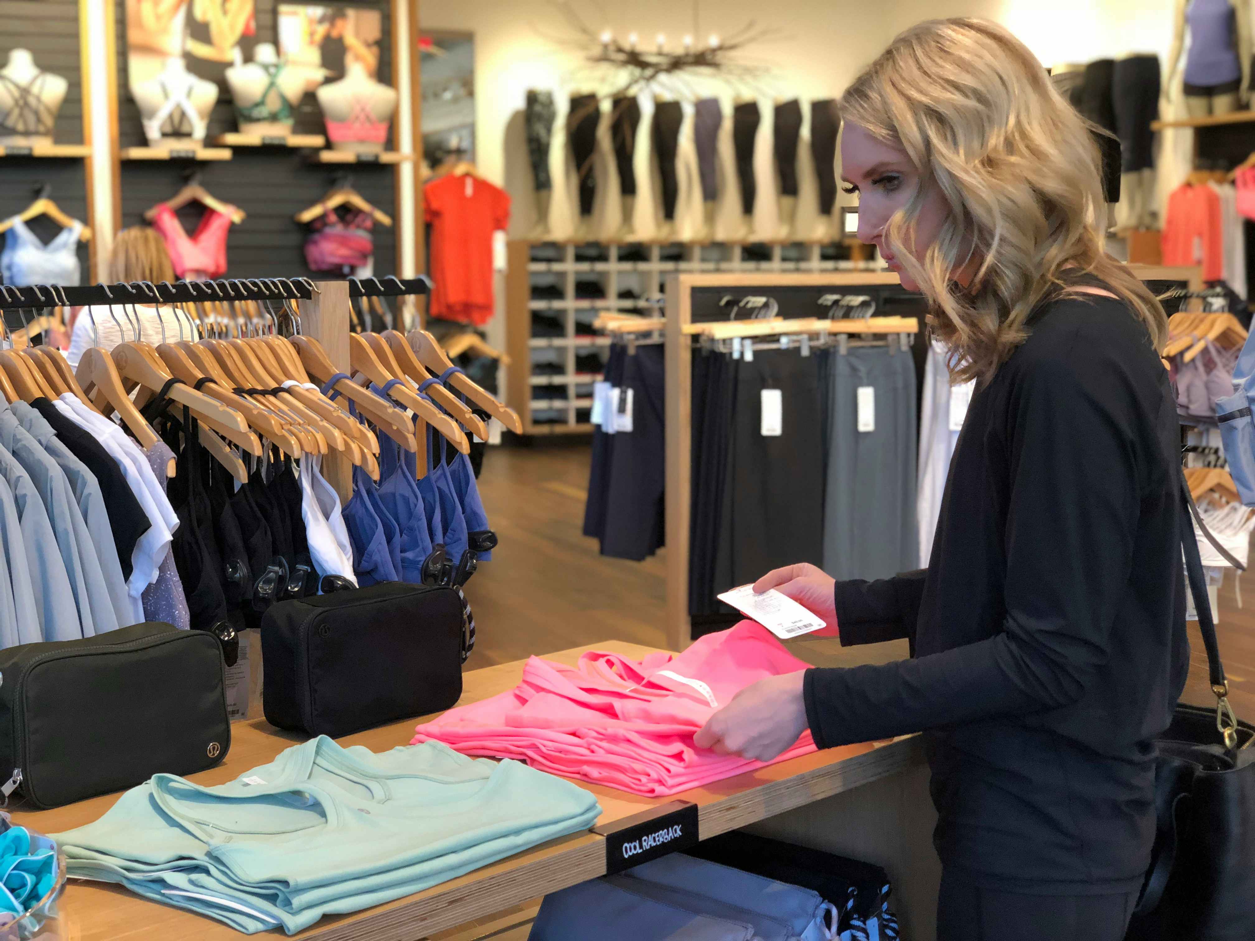 Woman looking at a stack of tank tops as if she's deciding on a color