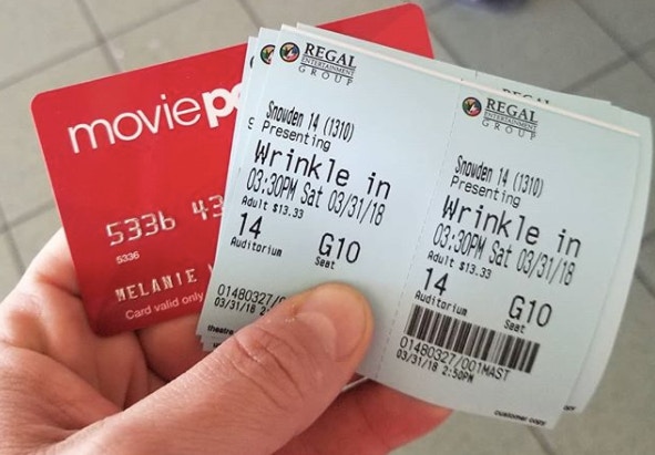 A person holding an old MoviePass card and tickets to a movie.