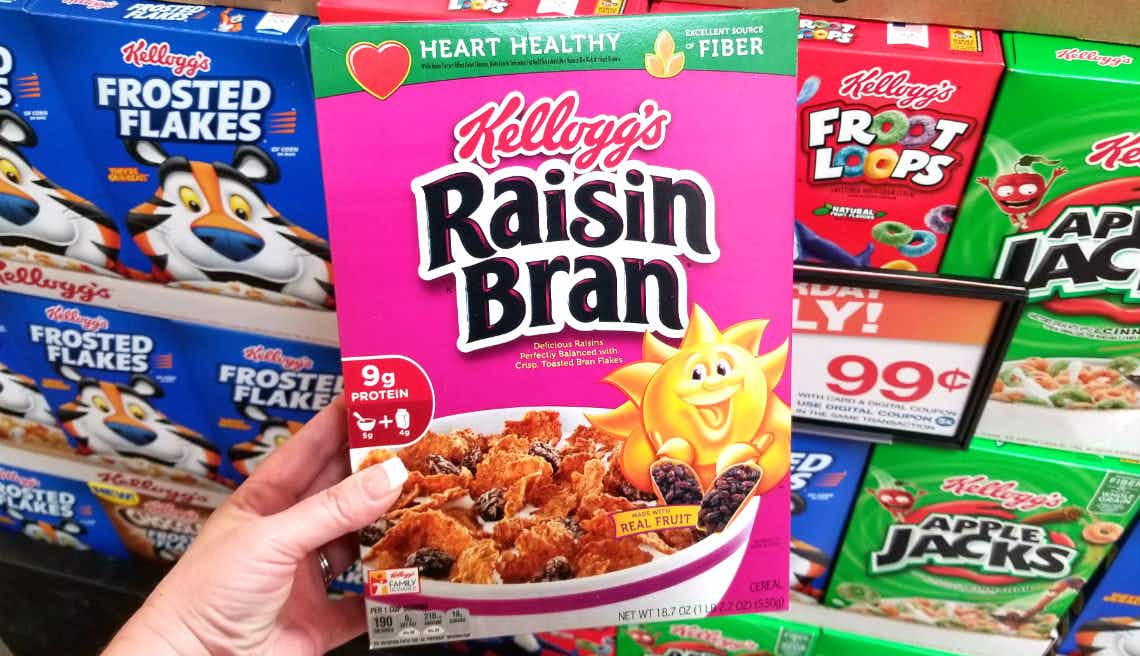 Hand holding a box of Raisin Bran Cereal