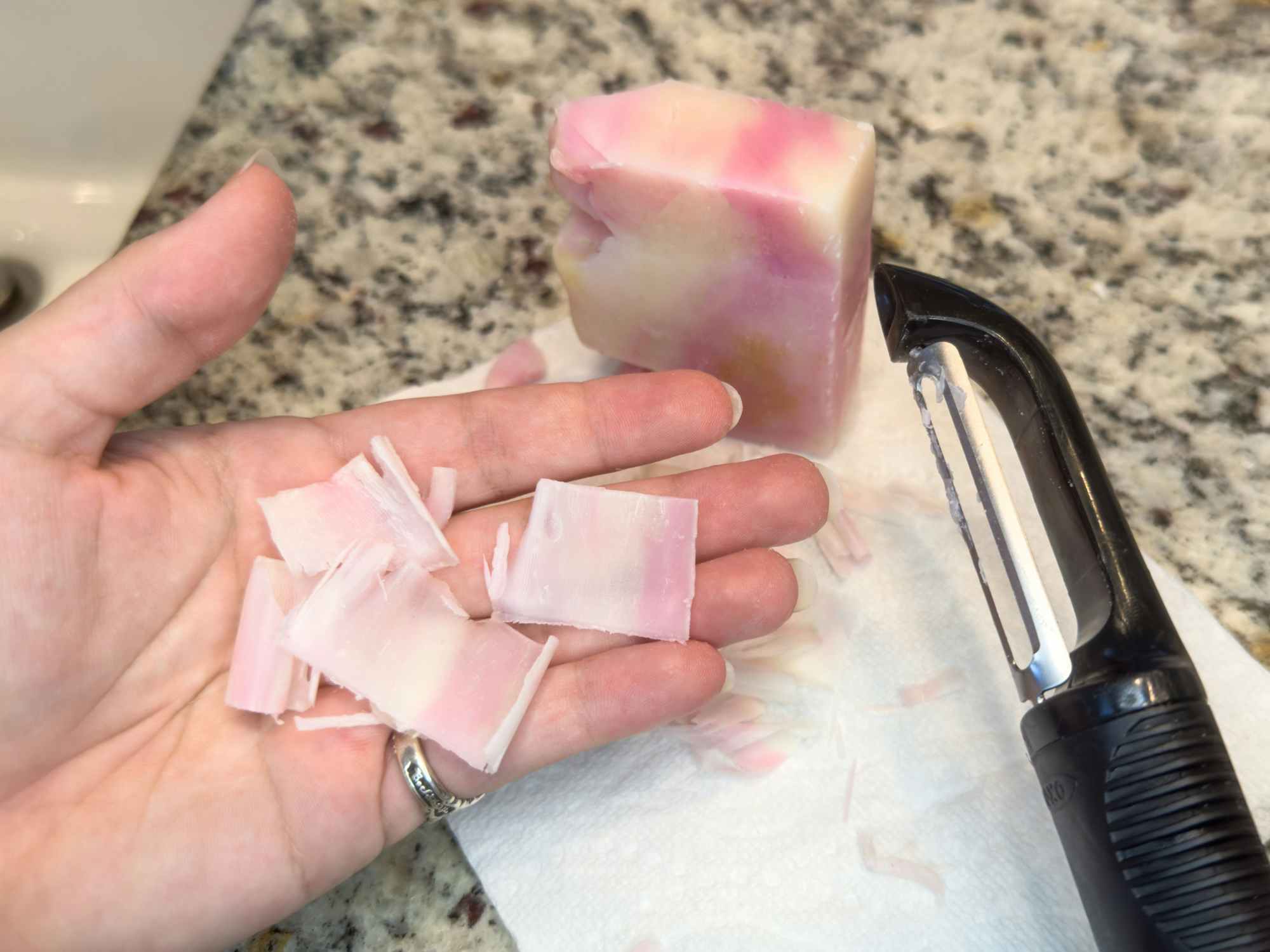 Someone using a vegetable peeler to make single use soap squares