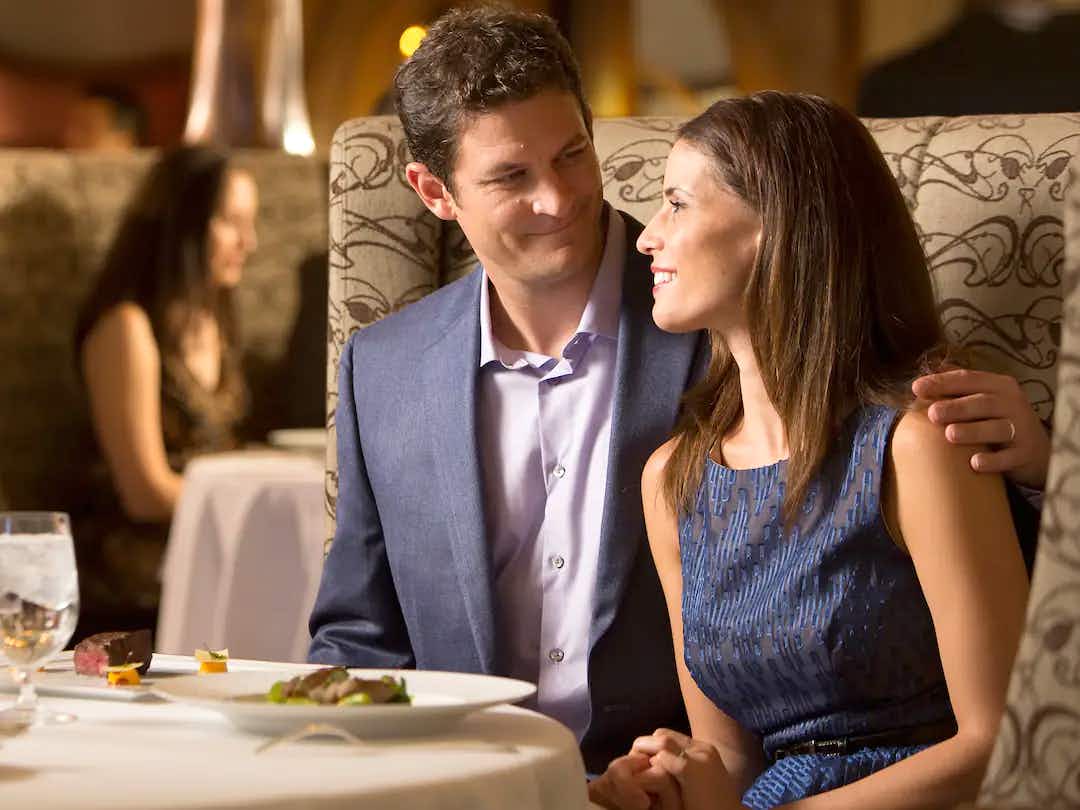 a couple at a table at one of disney cruise lines adult-exclusive on-board restaurants
