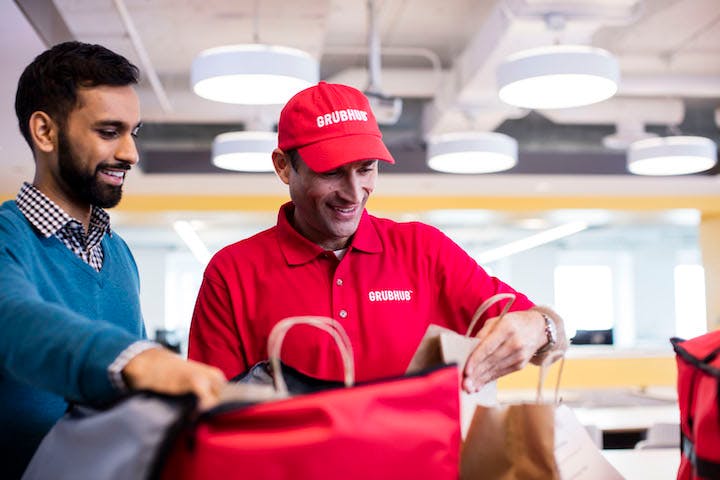 Grubhub delivery man smiling while reviewing an order