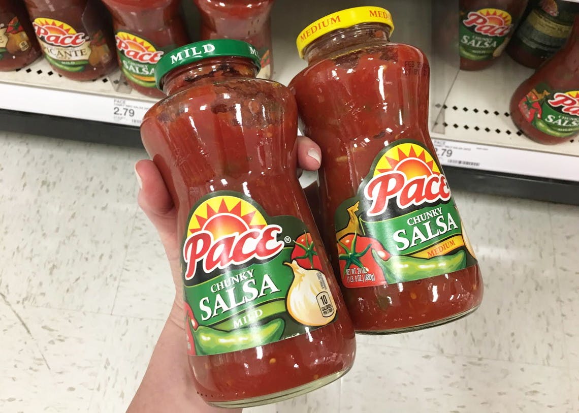 Two bottles of Pace Salsa held in a grocery store aisle. 