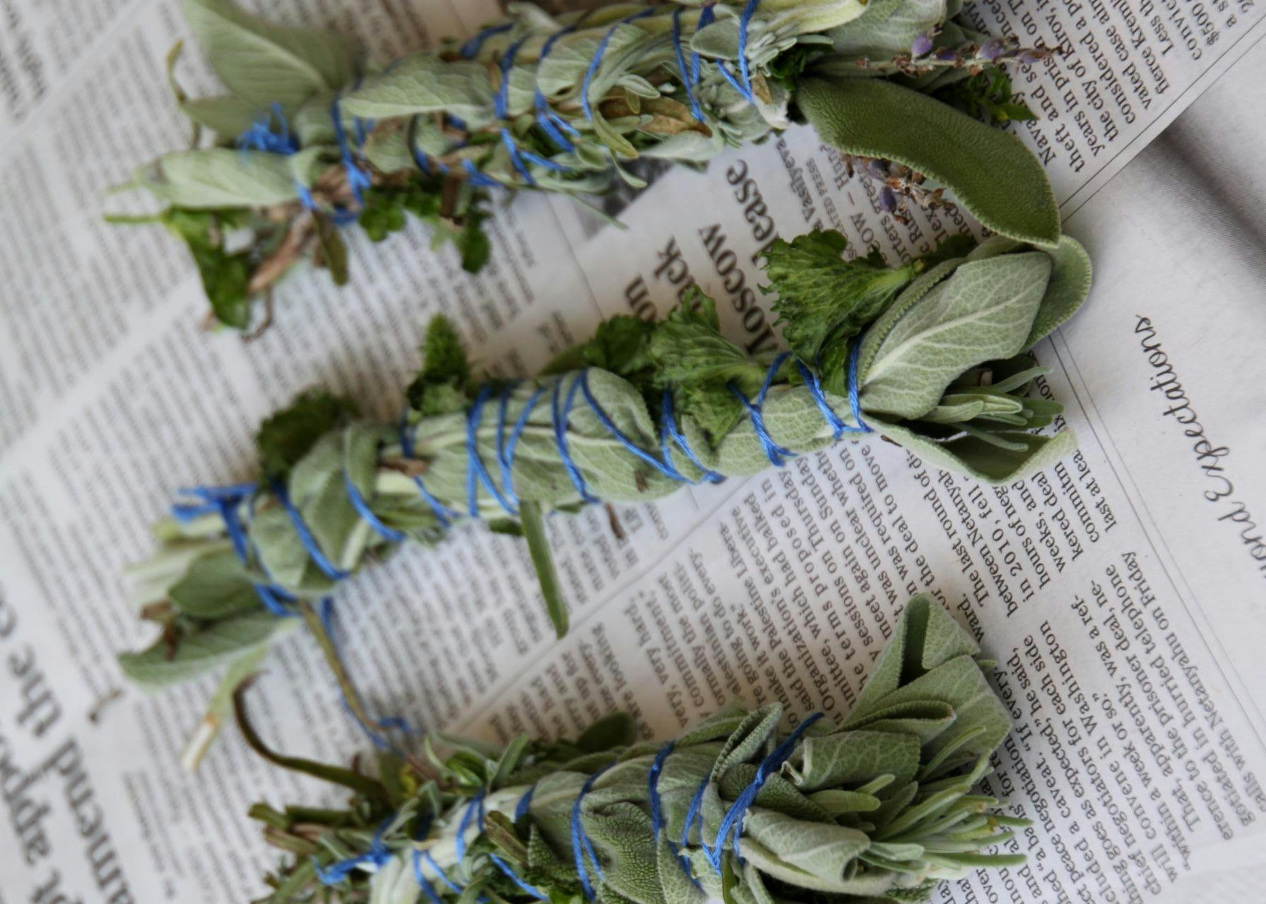 Some herbs bundled together on top of some newspaper.
