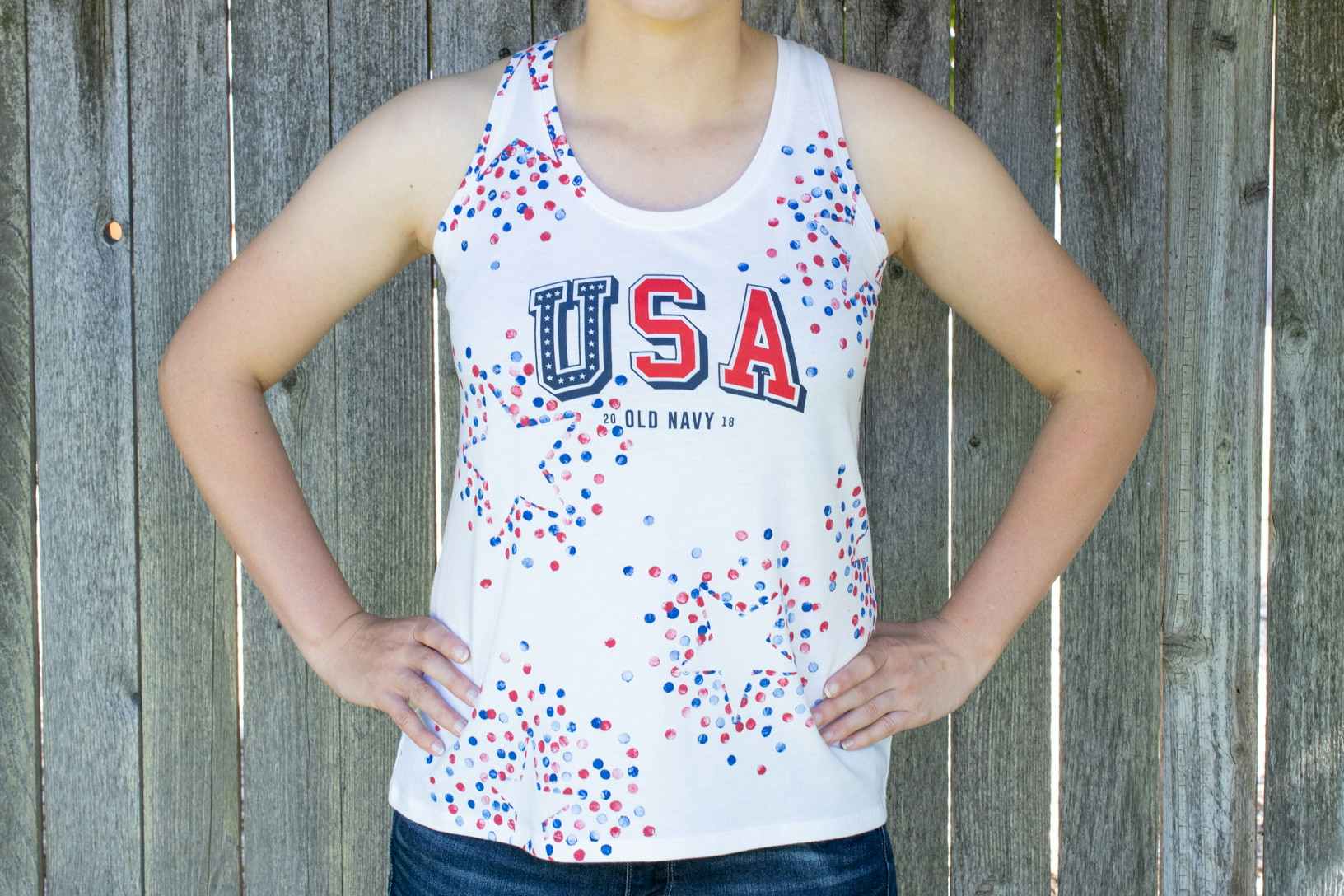 A person wearing a white Old Navy USA tank top with stars stenciled on in red and blue.