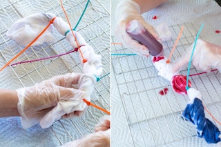 A person's gloved hands fastening zip ties around the rolled up Old Navy baby onsie and applying the different colored dye to each section.