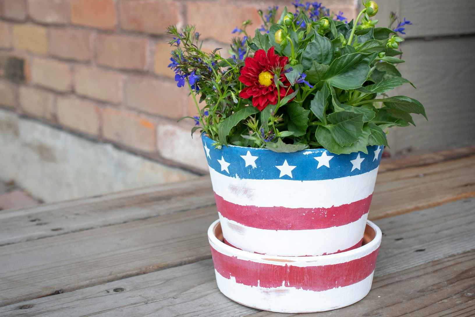 A terracotta plant pot painted to look like an American flag with star stickers.