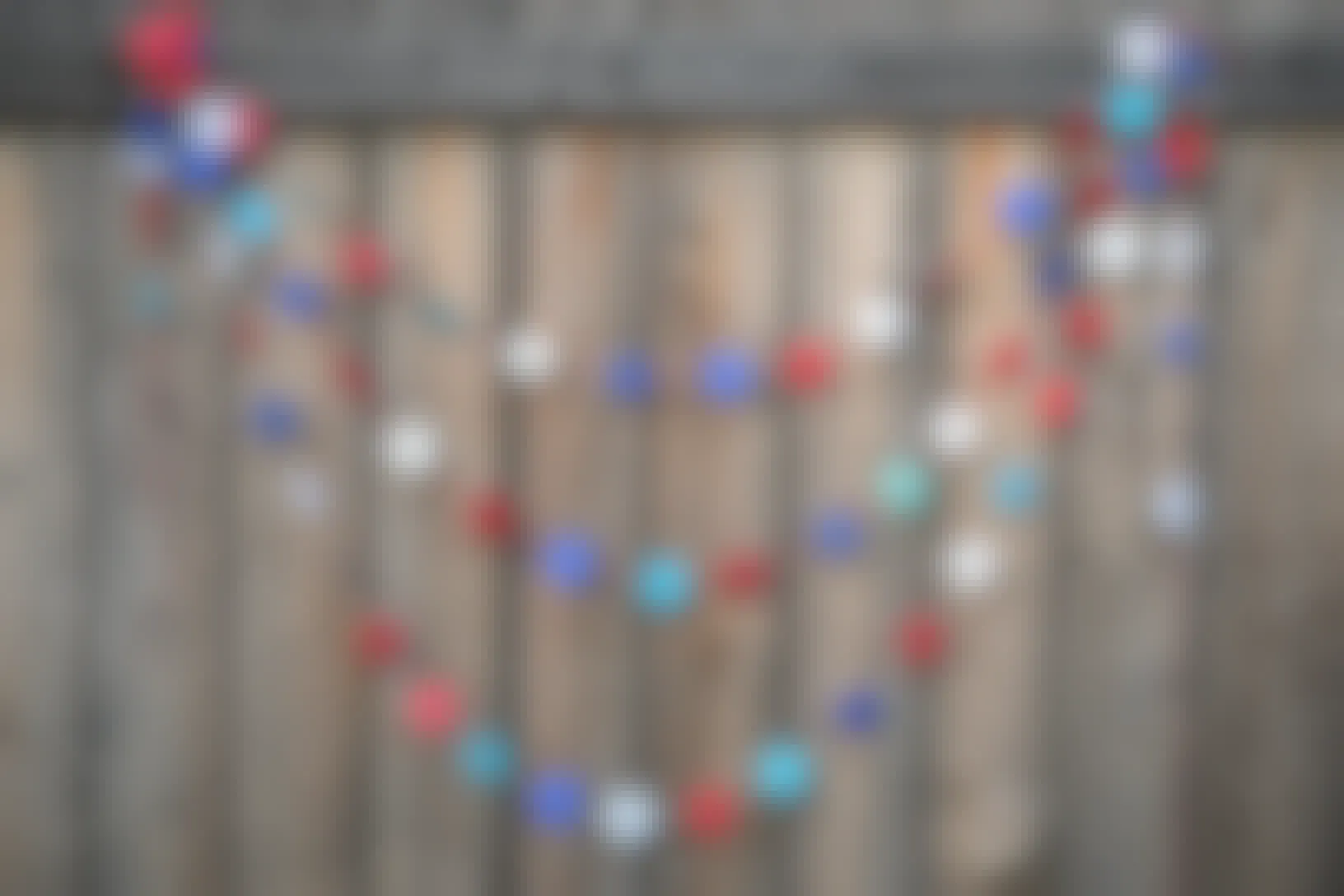 A DIY red, white, and blue star garland hanging from a wooden fence.