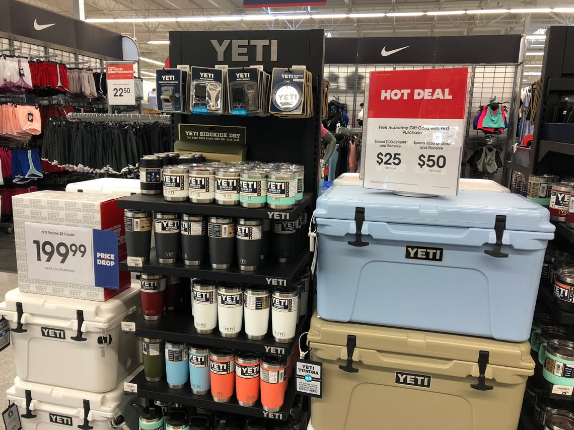 A YETI display and stack of YETI coolers with a sale sign on top inside Academy Sports.