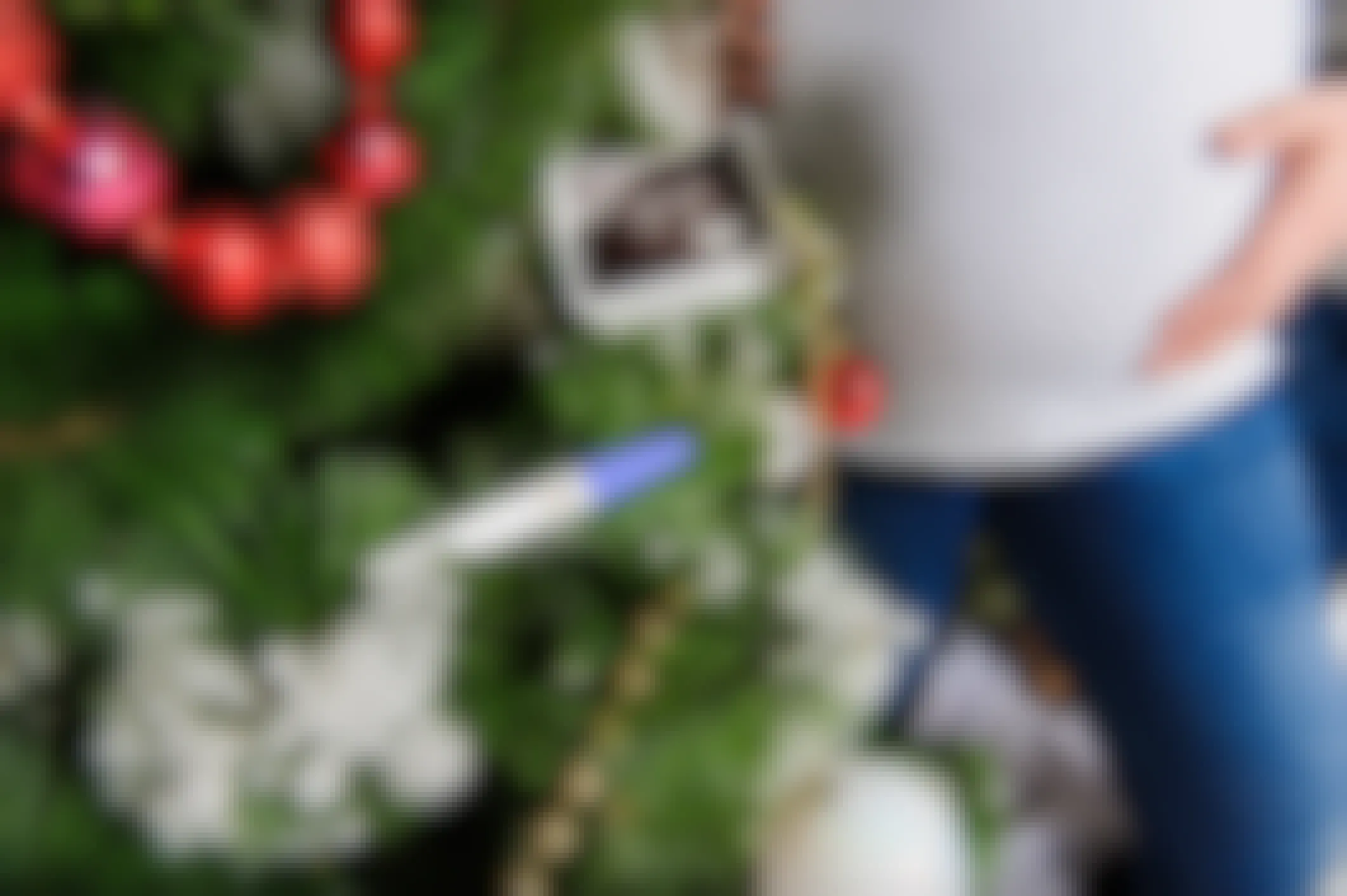 A pregnant woman standing near a Christmas tree that has a sonogram photo and positive pregnancy test on it.