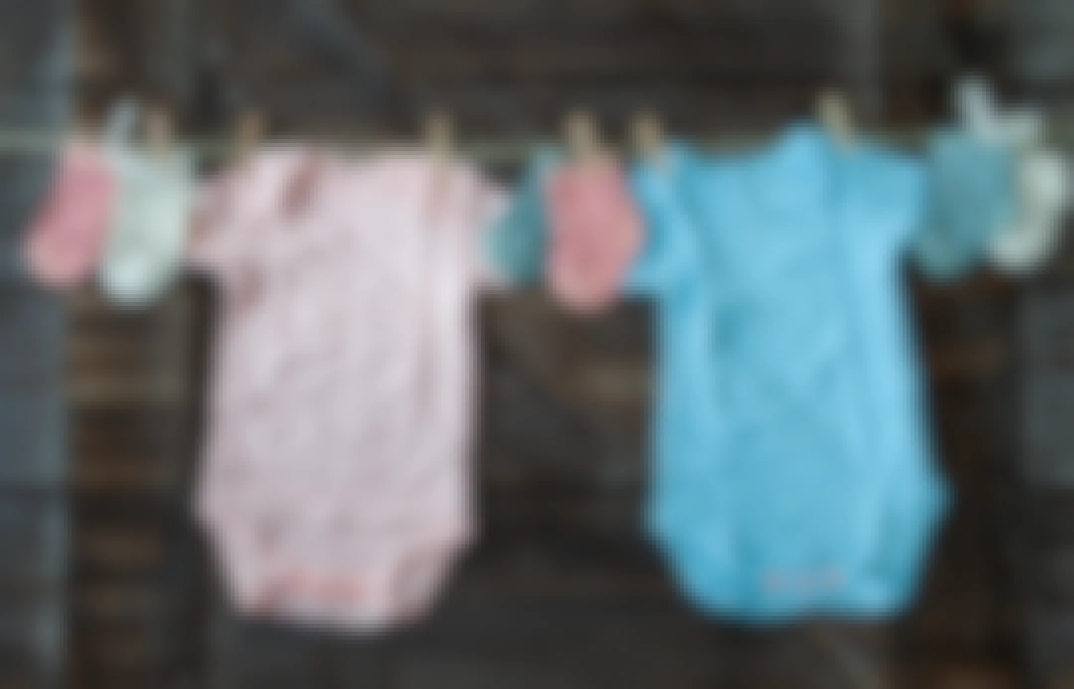Baby clothes pinned to a clothesline with a wooden background.