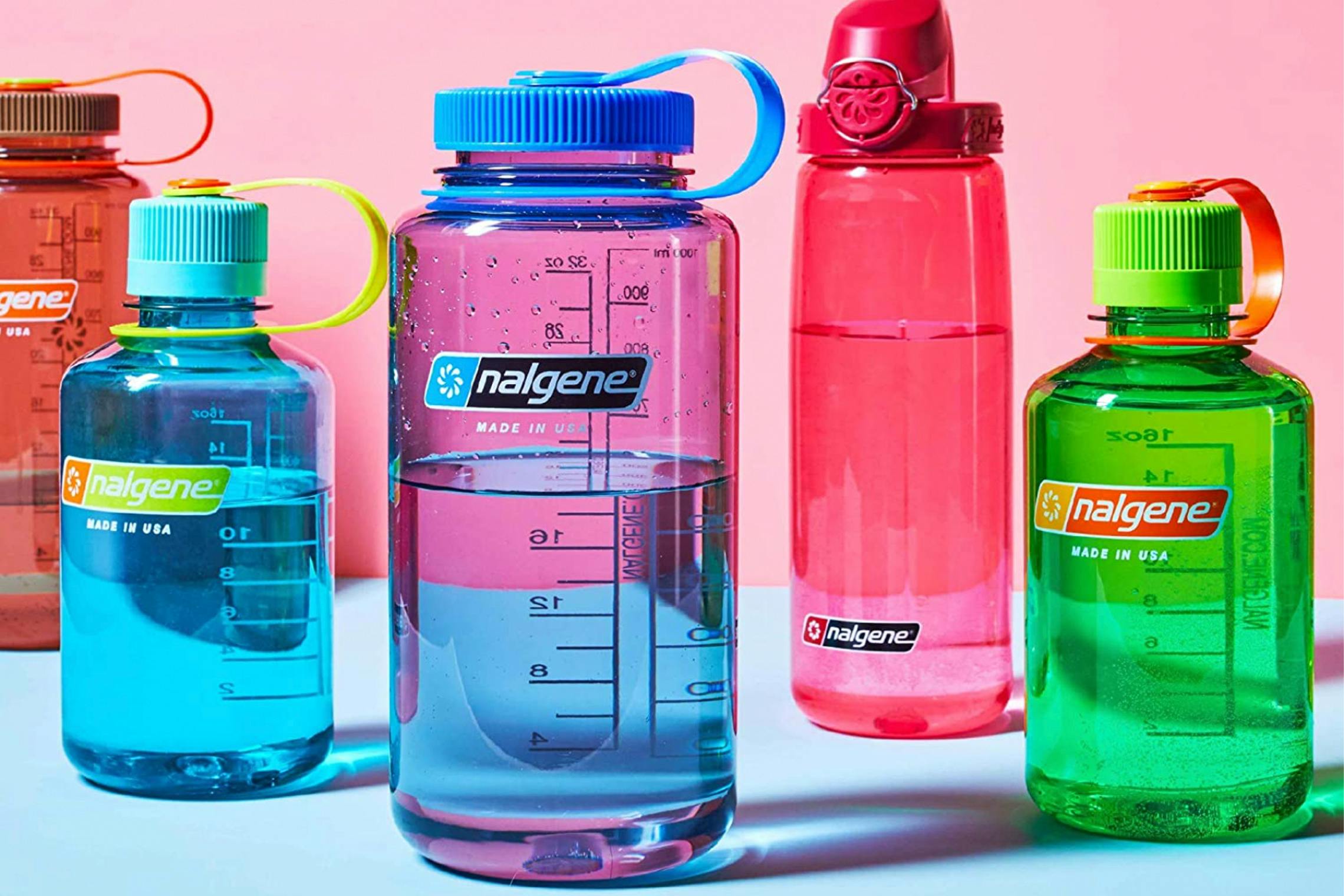5 Nalgene water bottles in front of a pink background