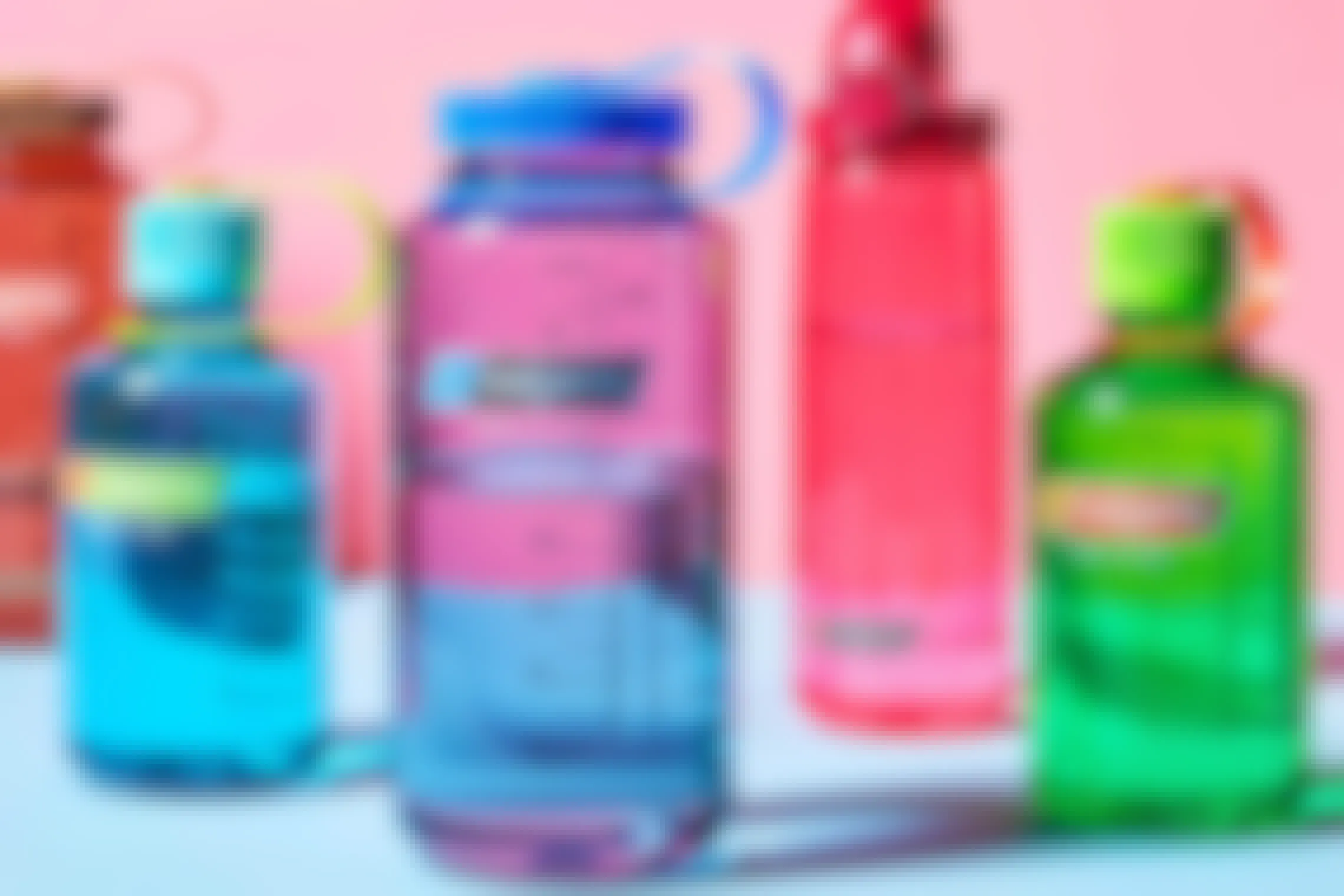 5 Nalgene water bottles in front of a pink background