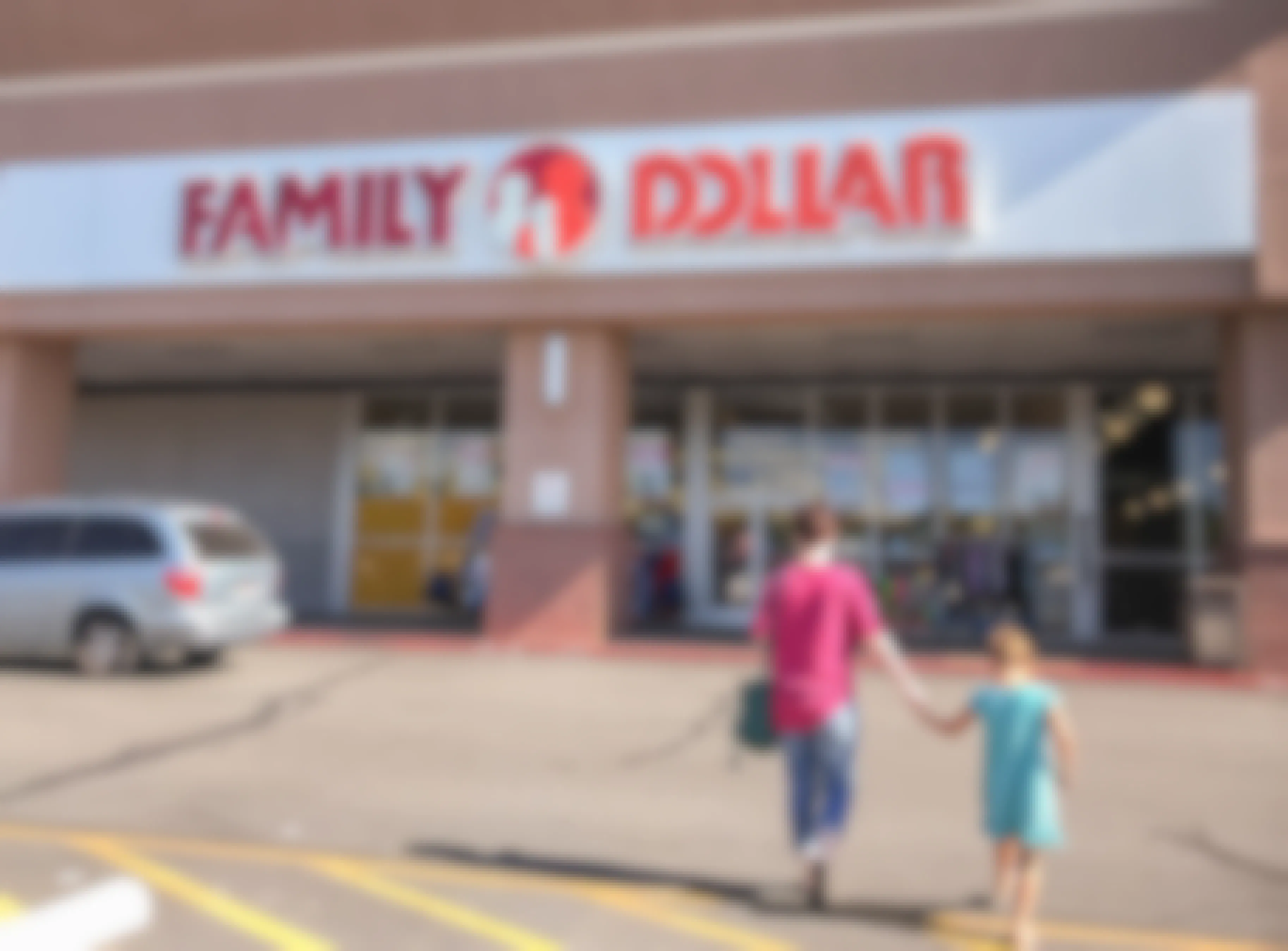 Woman holding hands with a child, walking into a Family Dollar