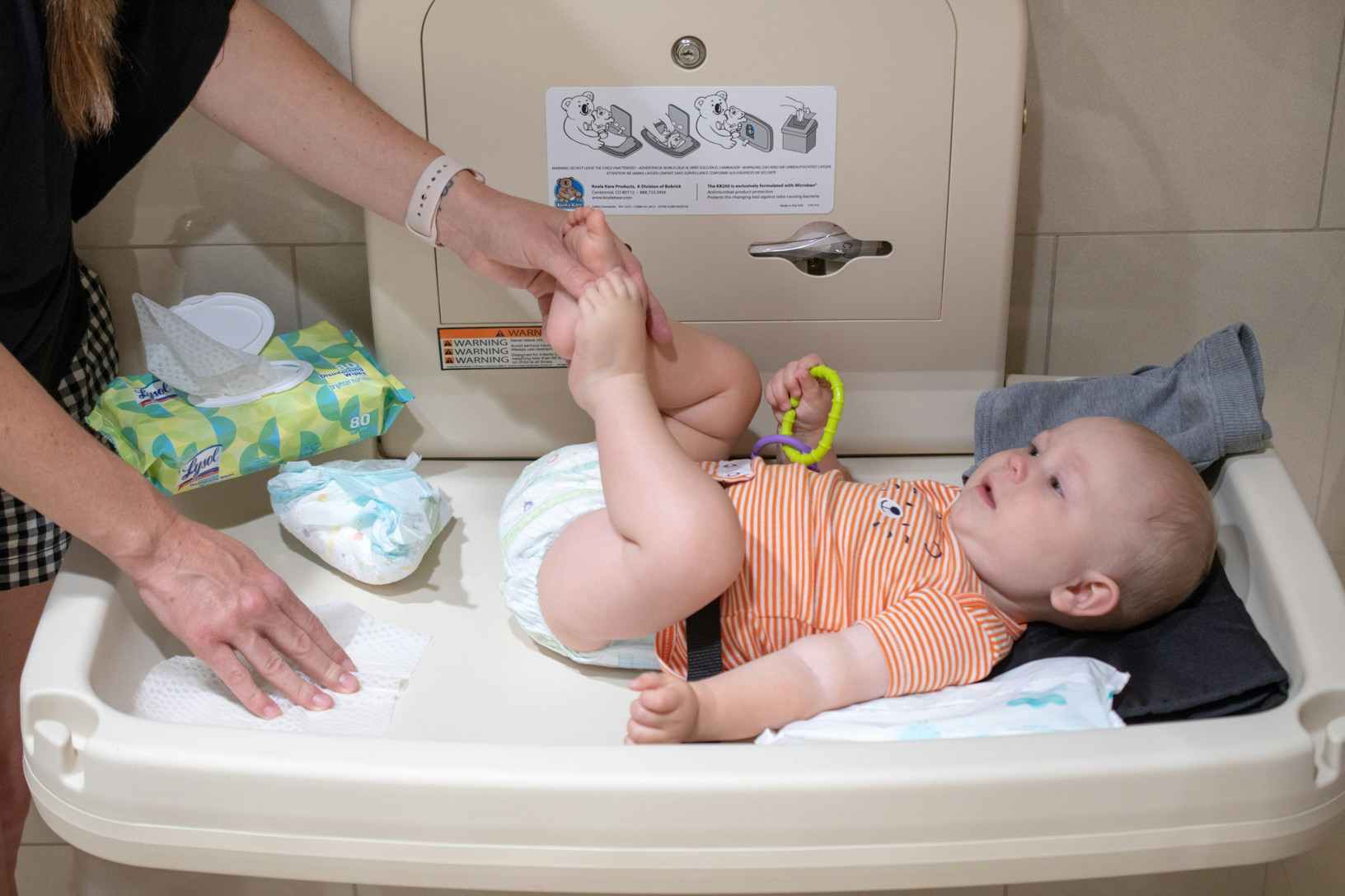 person wiping changing table with wipe before diaper change