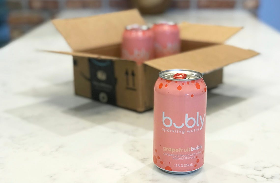 A can of Bubly sparkling water on a counter with two more cans in an Amazon box in the background.