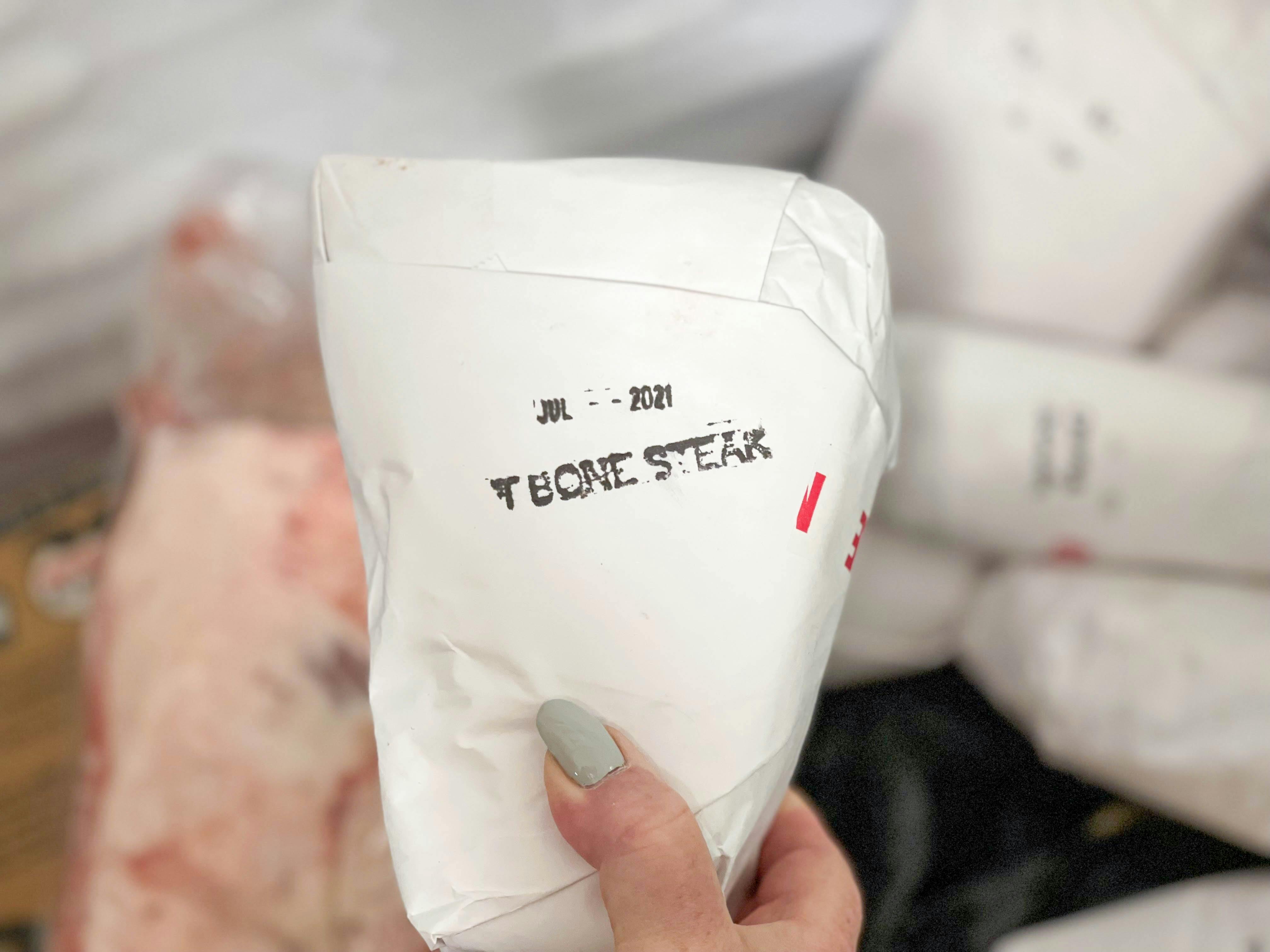 hand holding tbone steak in freezer