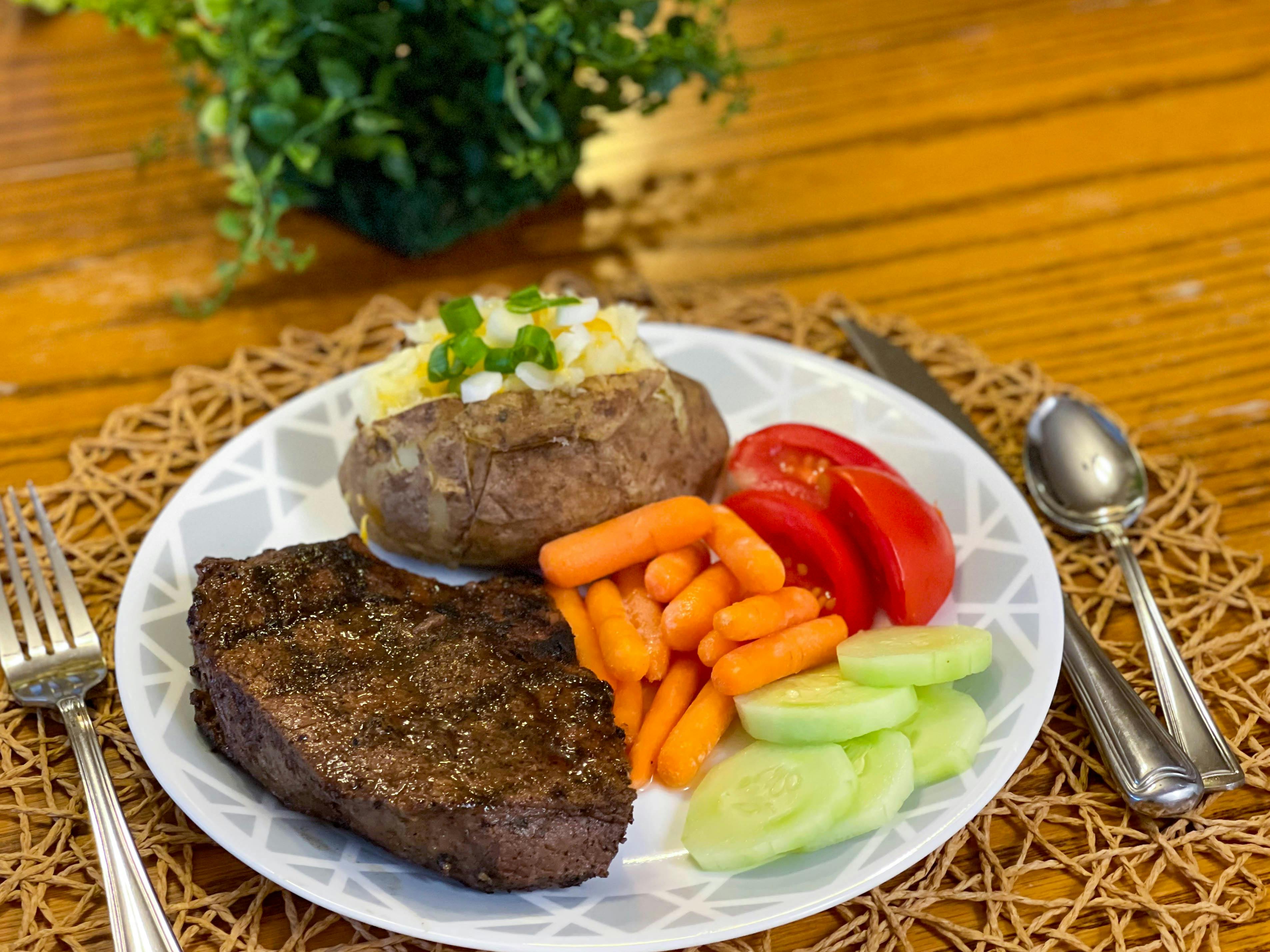 steak dinner on plate with vegetables