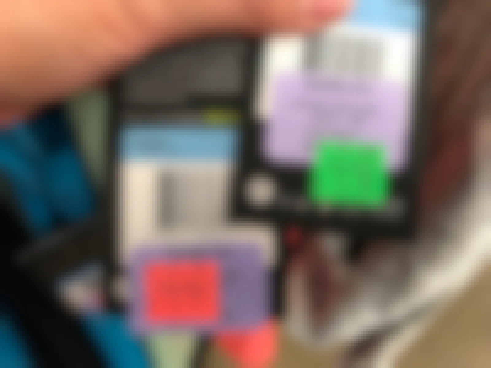 Two Nike tags being held up to show the prices, one with a red clearance sticker, and one with a green clearance sticker.