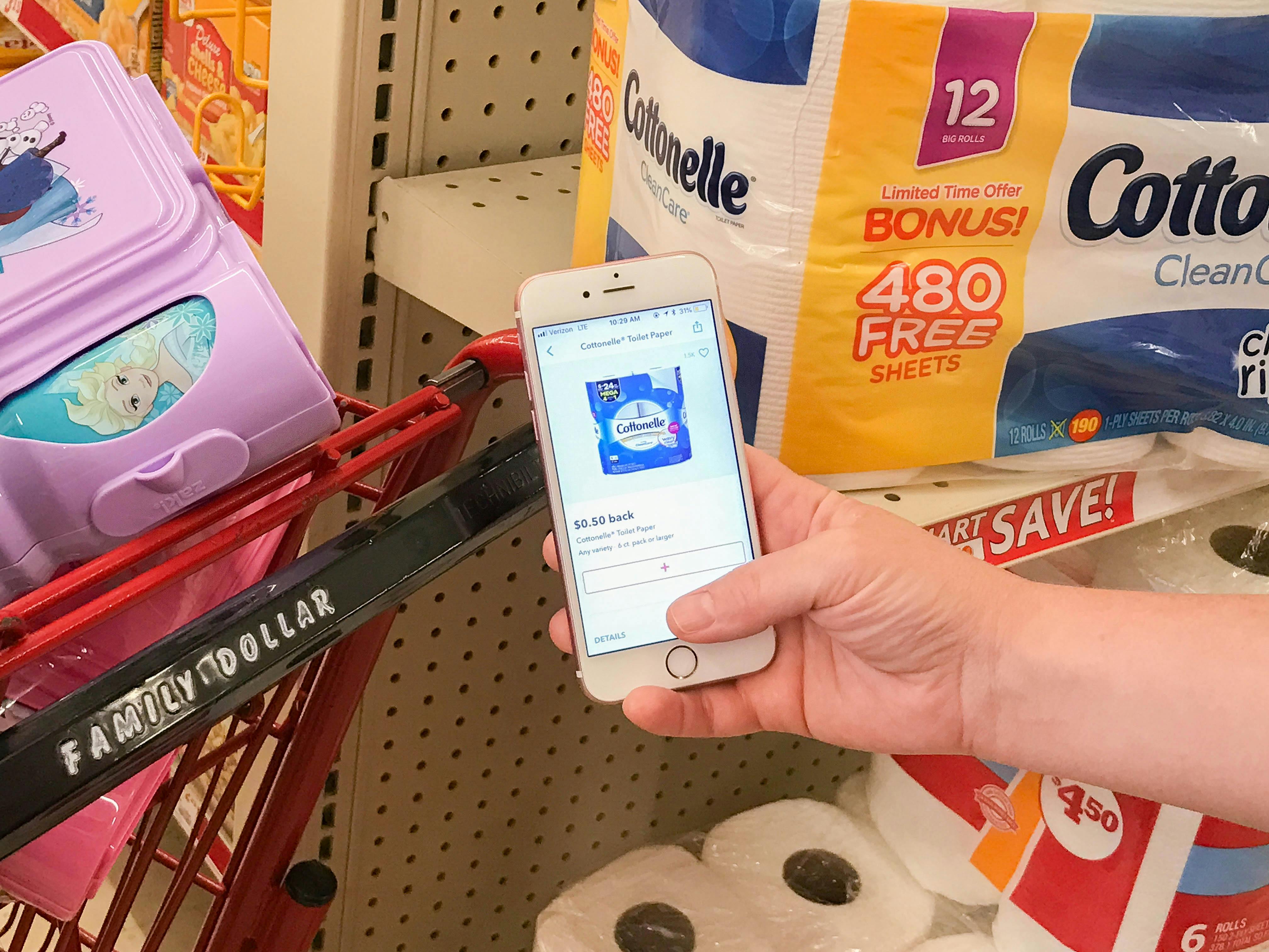 Woman holding a rebate app near toilet paper in a Family Dollar store