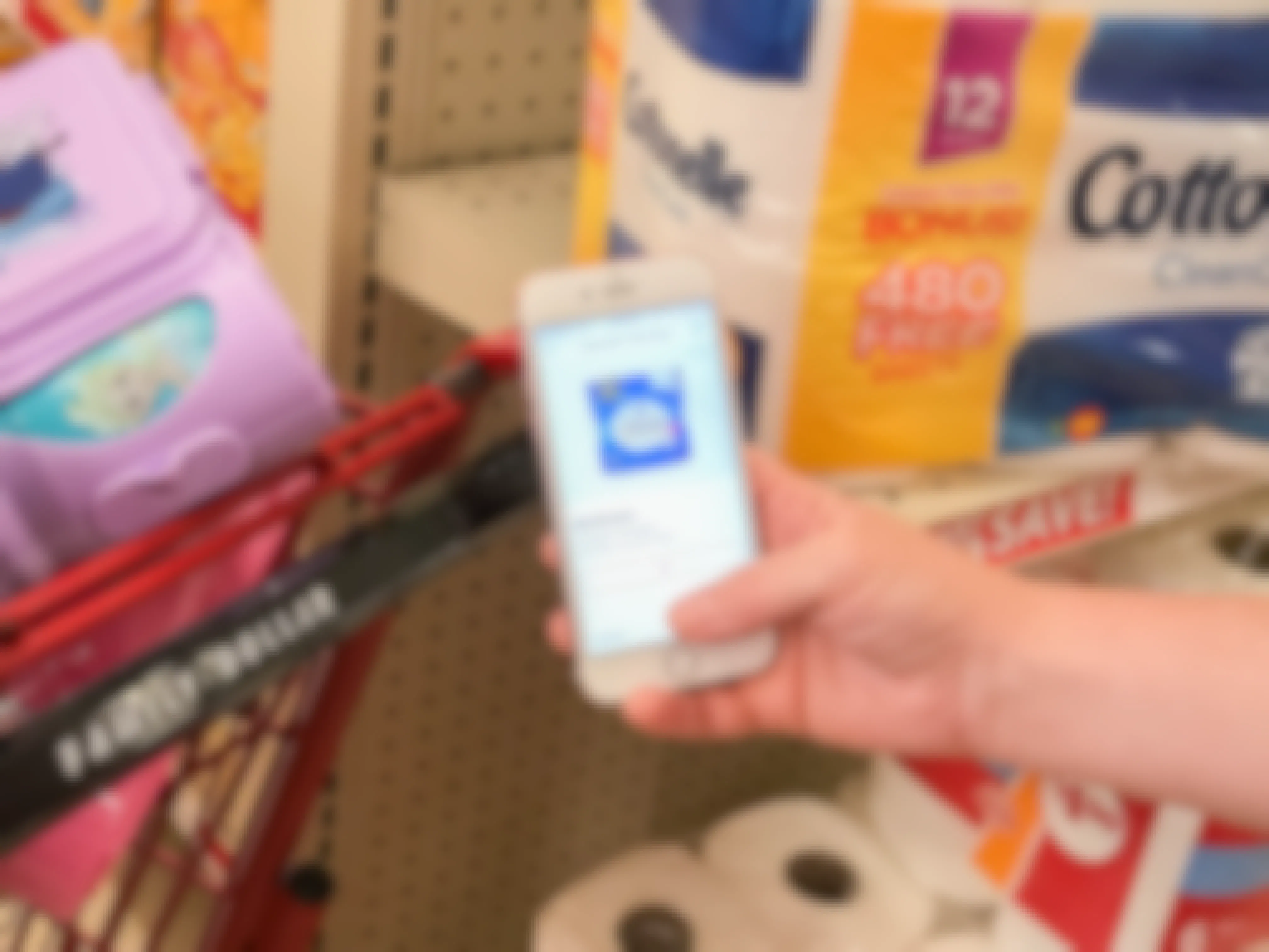 Woman holding a rebate app near toilet paper in a Family Dollar store