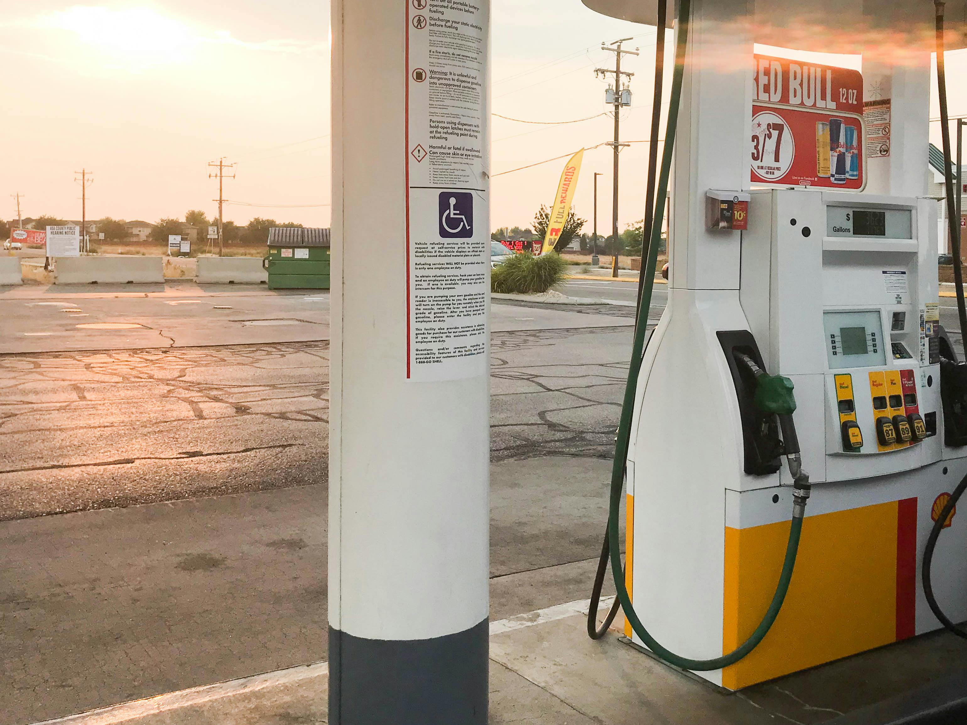 A Shell gas station pump next to an empty parking lot.