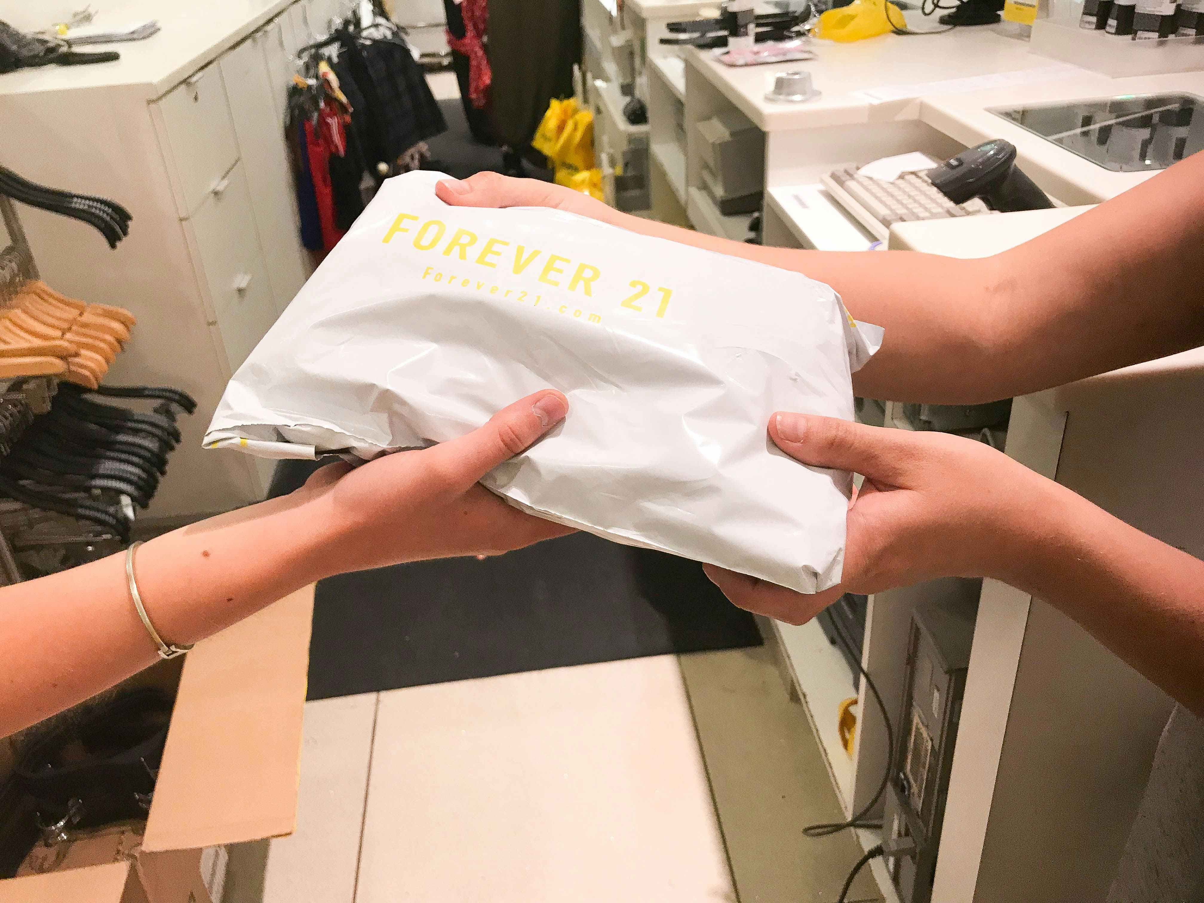 Someone handing a Forever 21 package to a Forever 21 employee