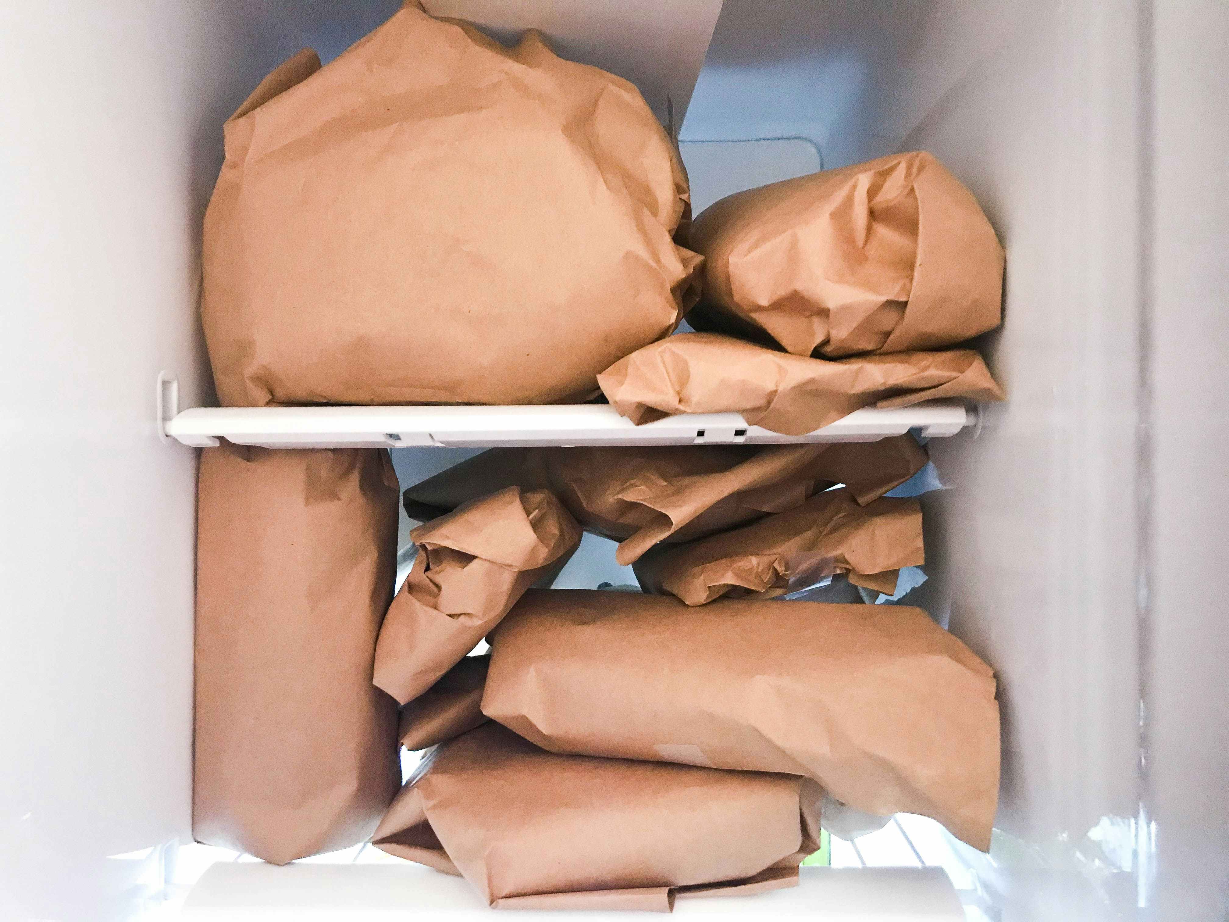 A freezer full of meat wrapped in brown paper.