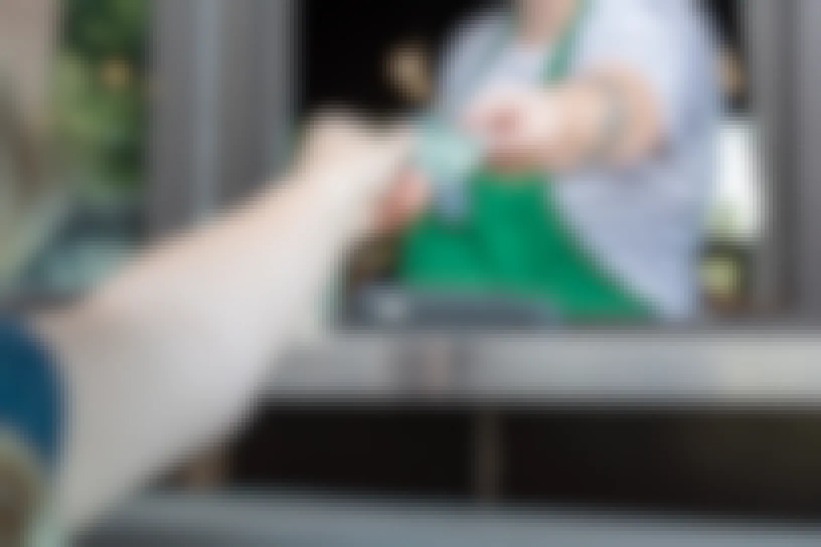A woman in a Starbucks drive-through taking a gift card from the barista at the window.