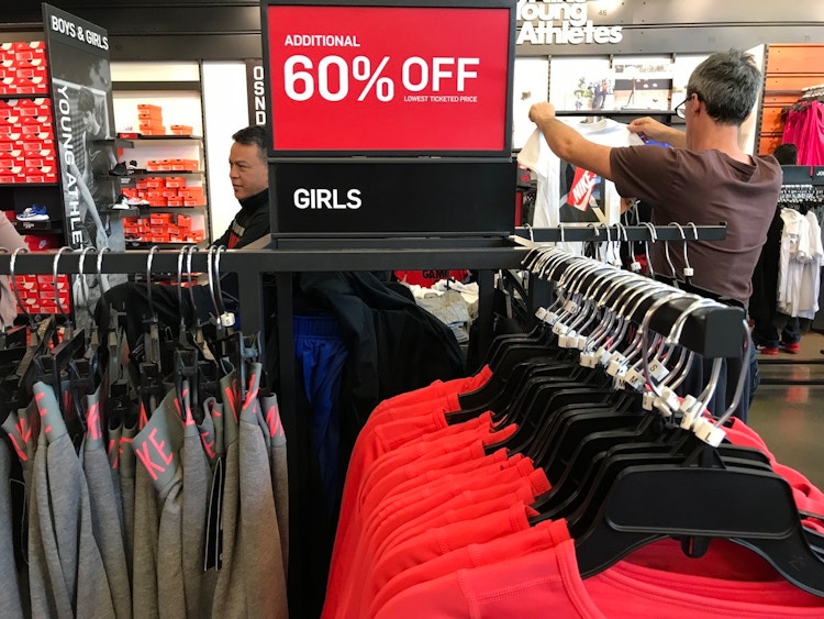 A sale sign on a Nike clothing rack for girls clothing that reads, "Additional 60% off lowest ticketed price
